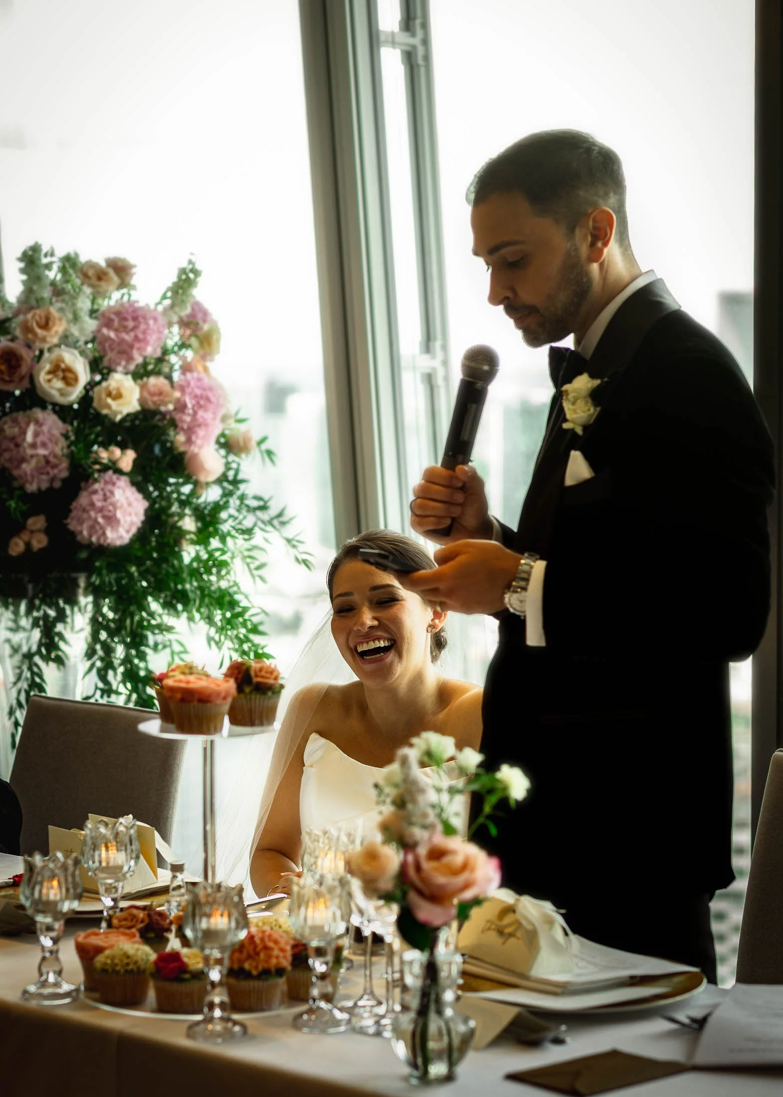 Candid moments during London wedding speeches as the bride laughs whilst looking at the groom.