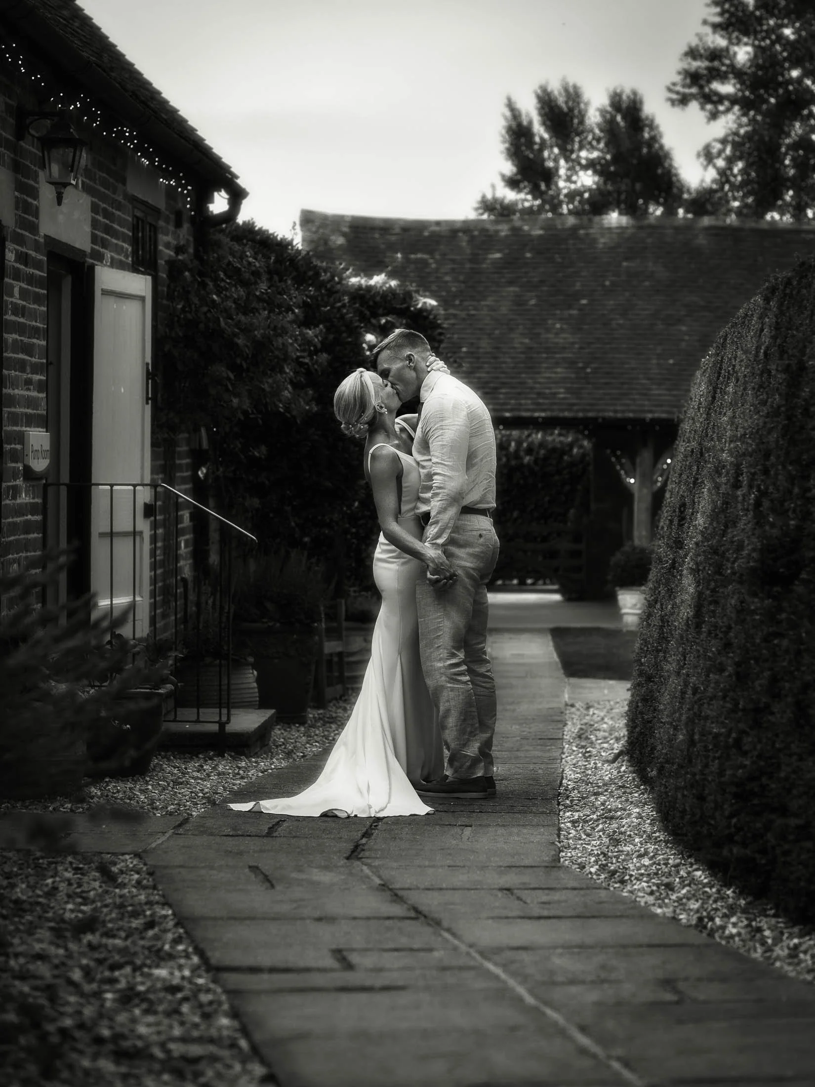 A black and white wedding photograph of a couple in the courtyard of Winters Barns in Canterbury, Kent, during their portrait session.