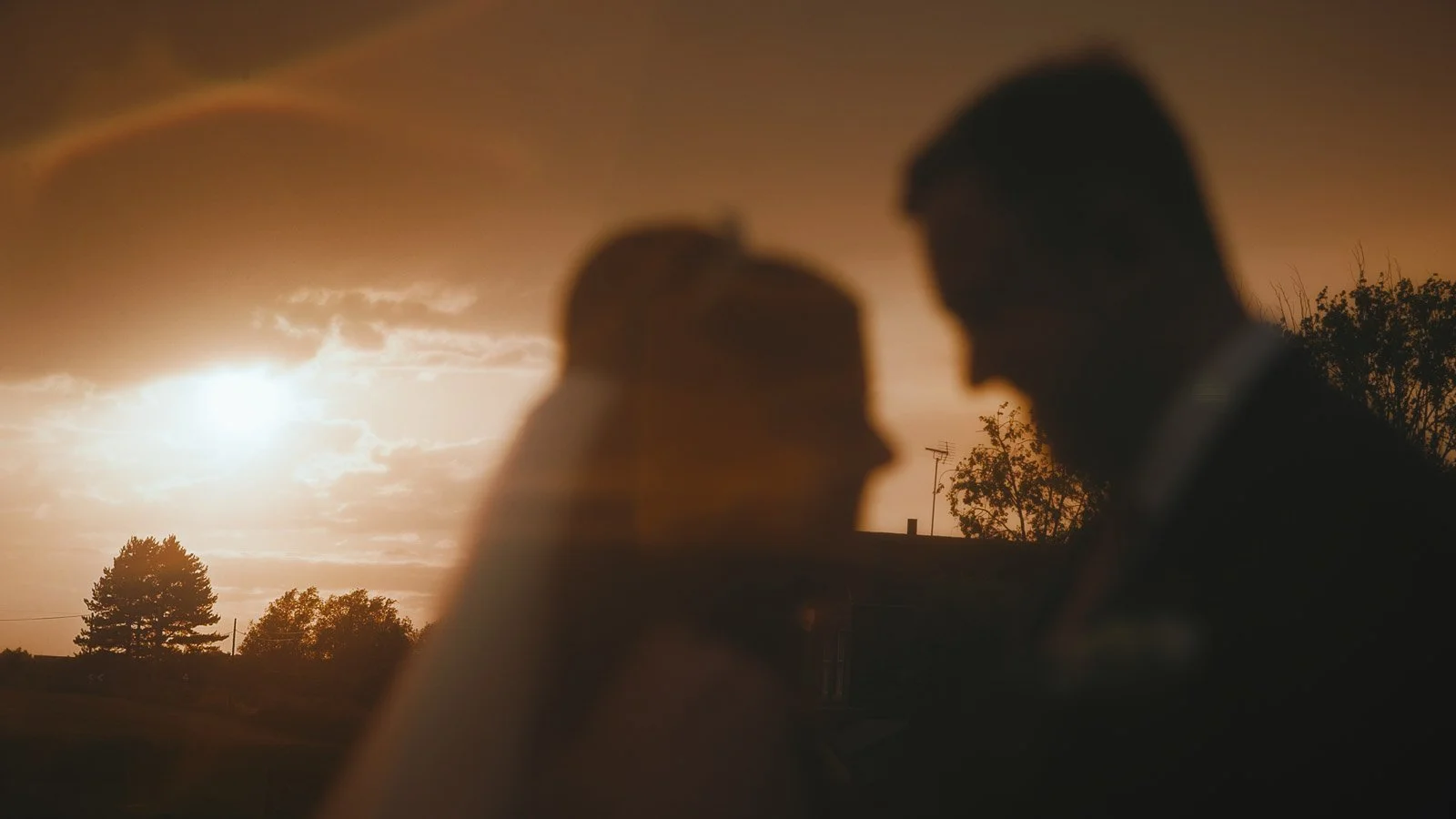 A cinematic shot of a dramatic sunset with the couple silhouetted against it in a Cooling Castle Barn wedding film in Kent.