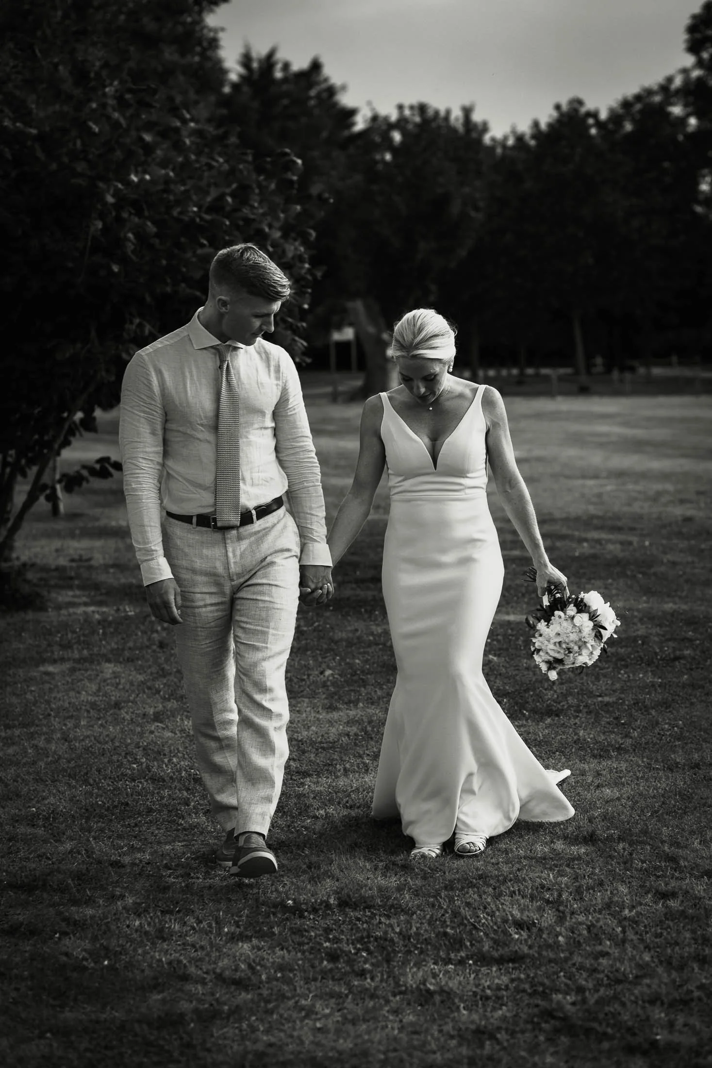 A natural light portrait of a bride and groom walking through the grounds of Winters Barns wedding venue on their summer wedding day.