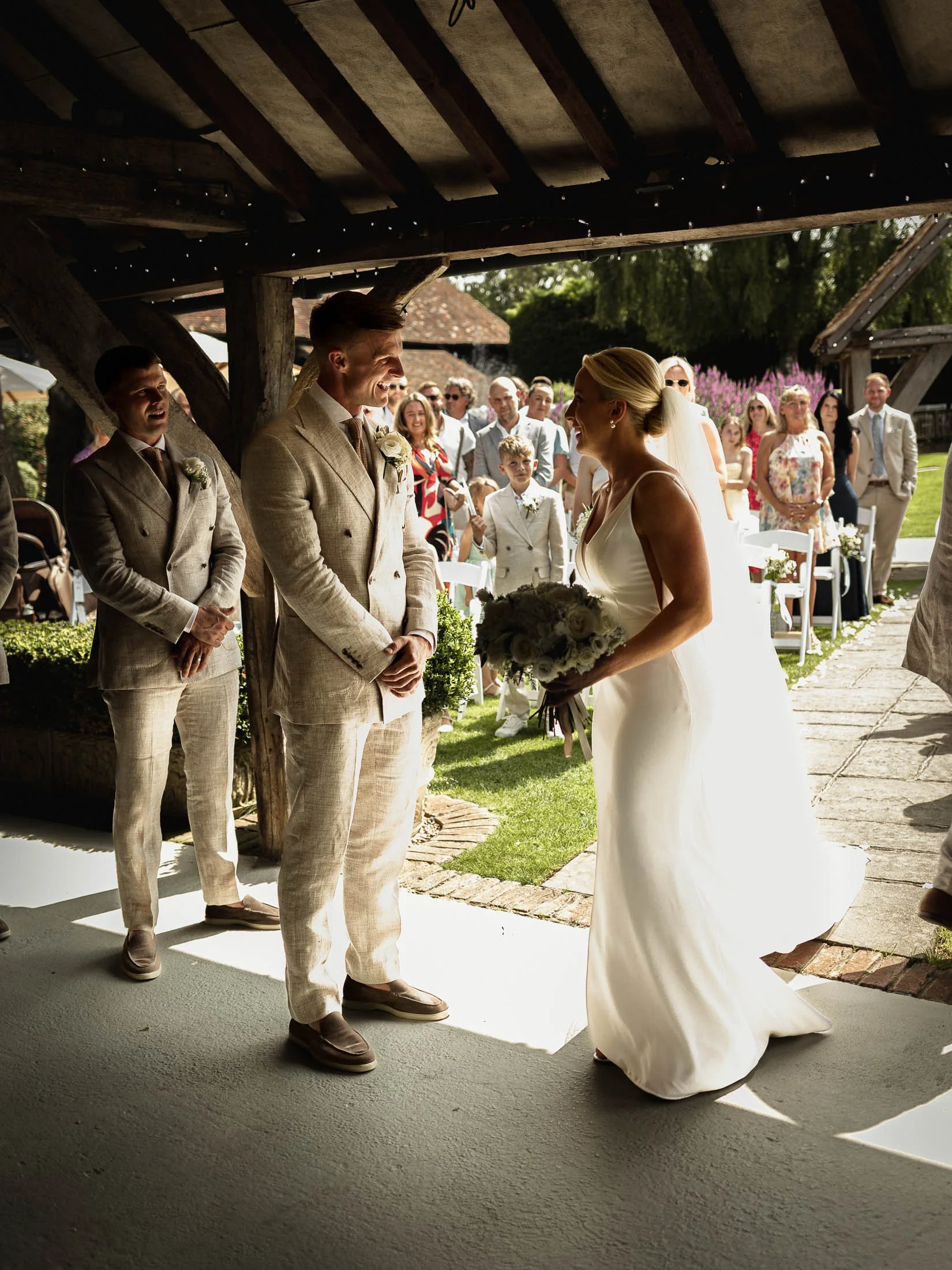 The grooms reaction to seeing his bride as she arrives at their summer outdoor wedding ceremony at Winters Barns.