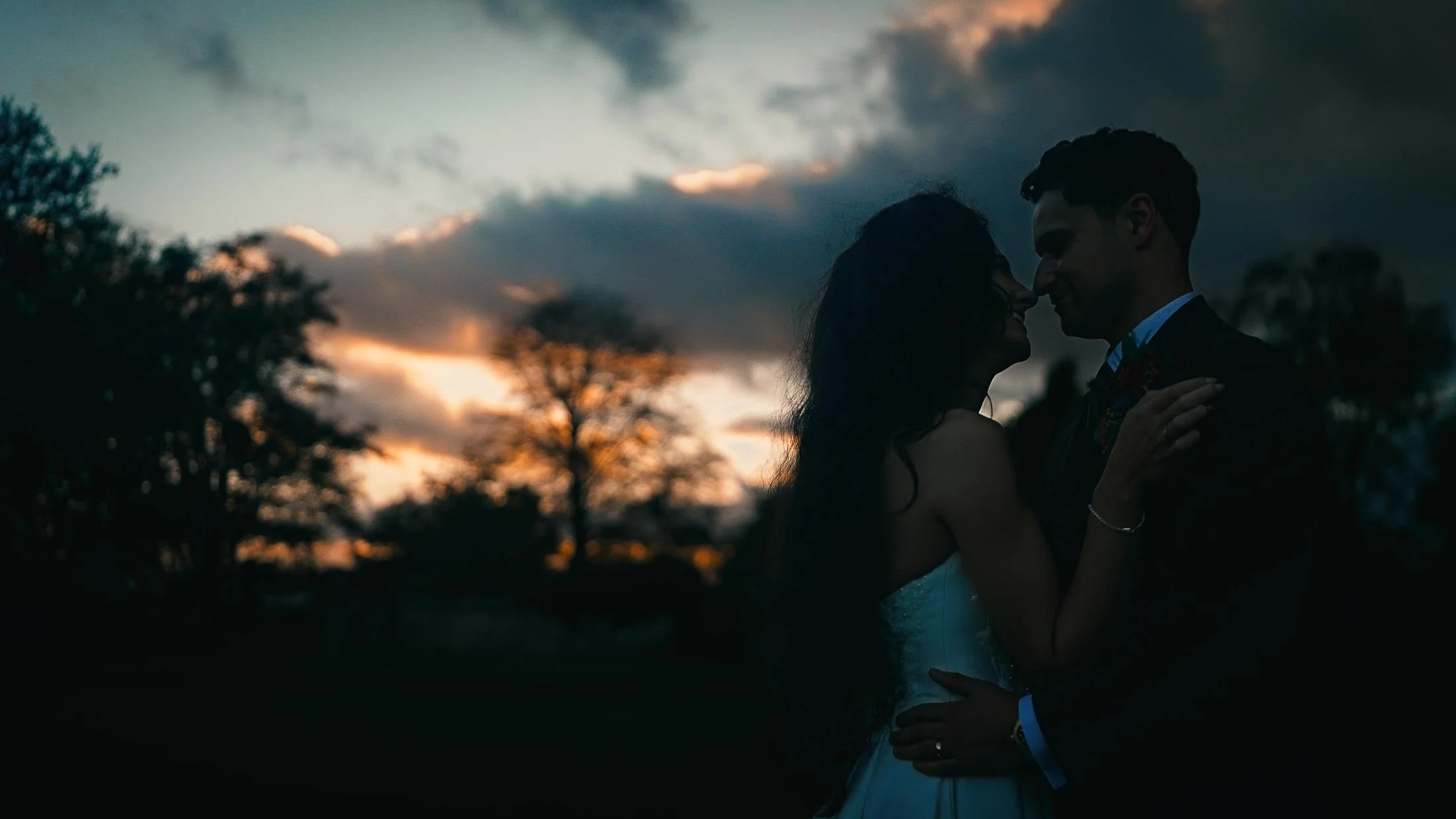 Dramatic sunset at Elmore Court wedding venue with couple silhouetted.