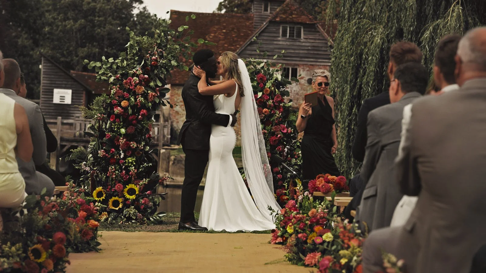 Editorial-style wedding photography from a colourful riverside celebration with bold florals and a marquee reception.