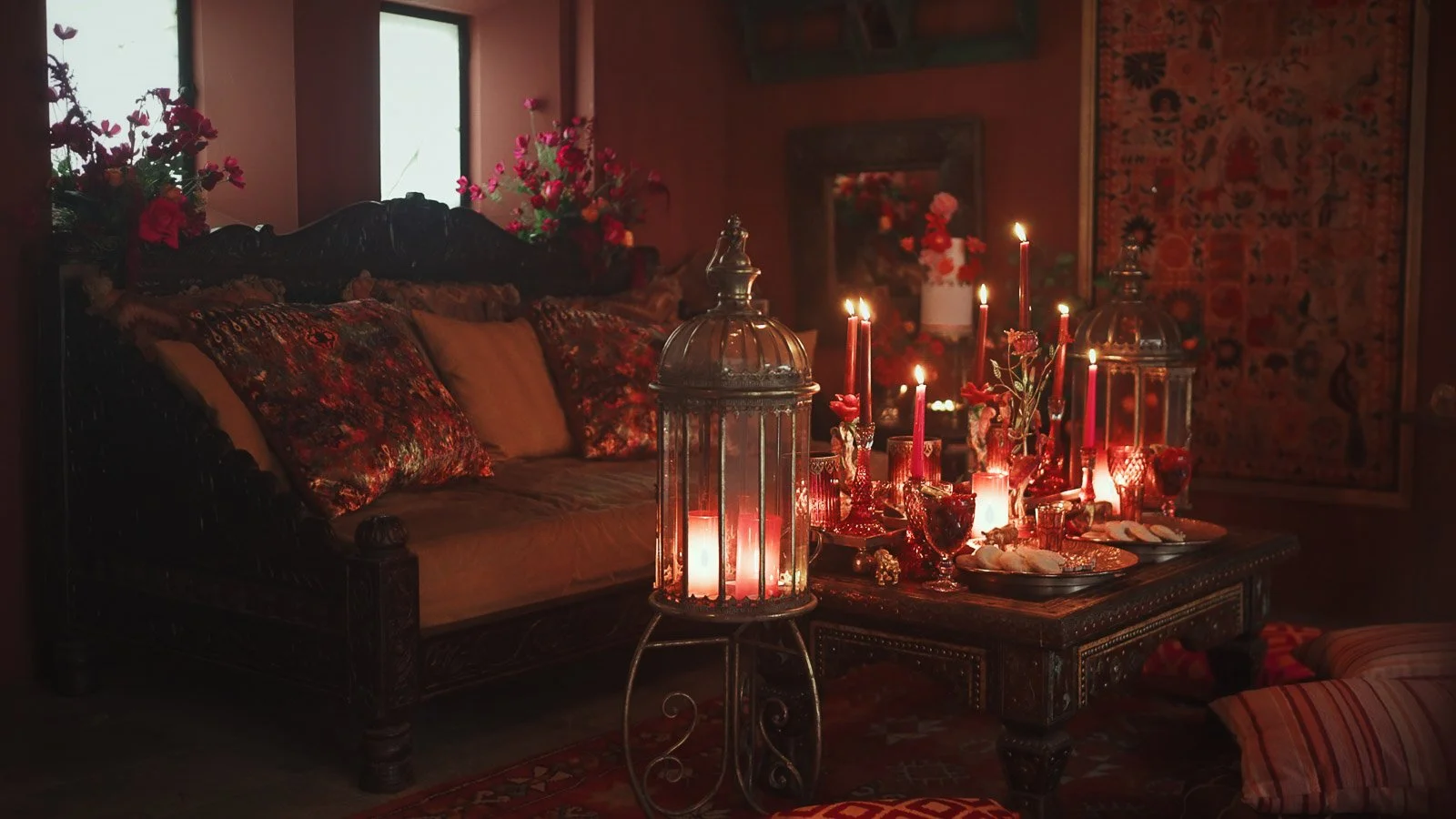 A red, pink and gold wedding breakfast setup and lit by candlelight in a fashion-forward wedding.