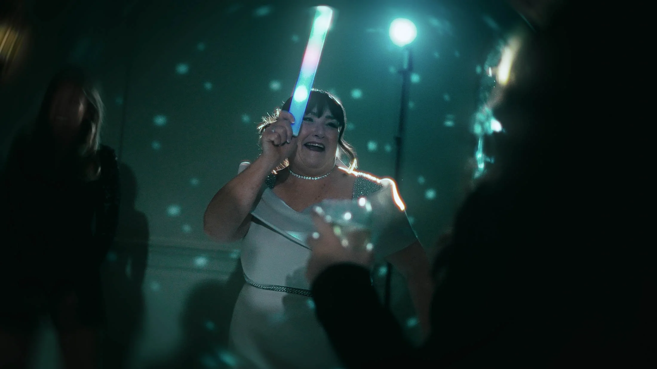 The Mother-of-the-Bride dances with a glow stick during high-energy evening celebrations on the dance floor.