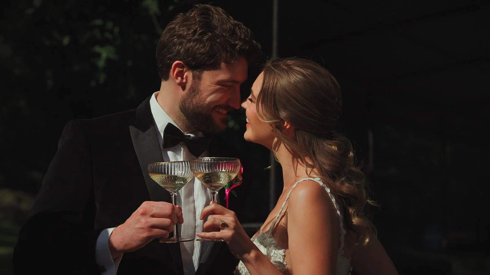 Modern black tie wedding look as the bride and groom touch foreheads and laugh together.