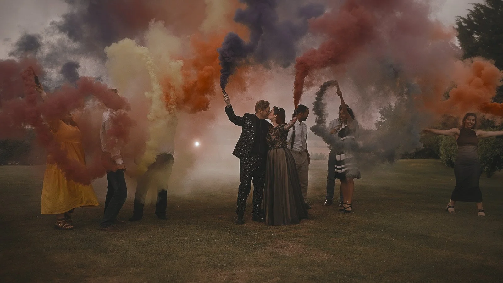 Wedding party holding smoke bombs for dramatic, cinematic portraits in the grounds