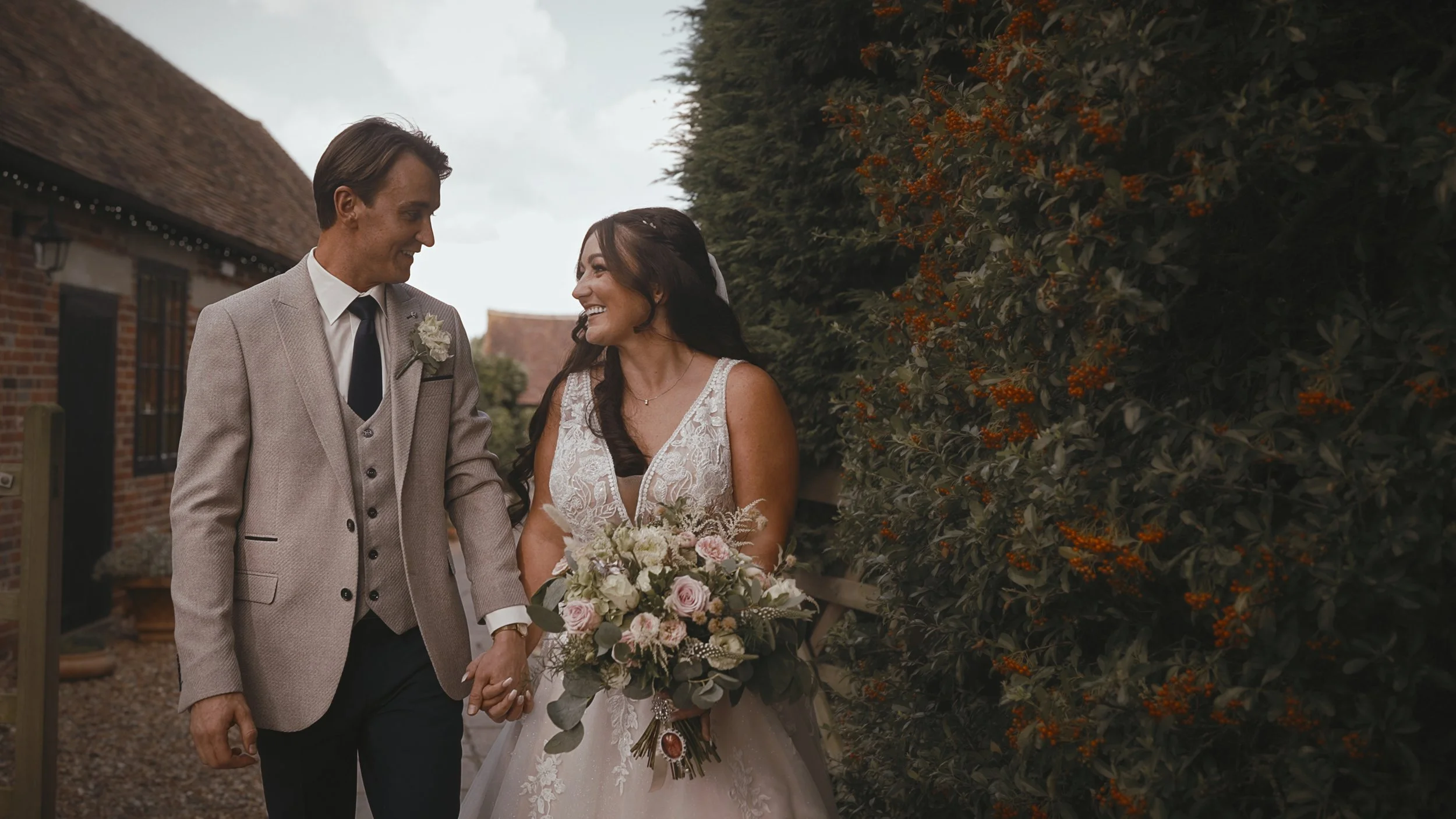 Bride and groom walk and talk to each other past the stables at Winters Barns wedding venue in Kent.