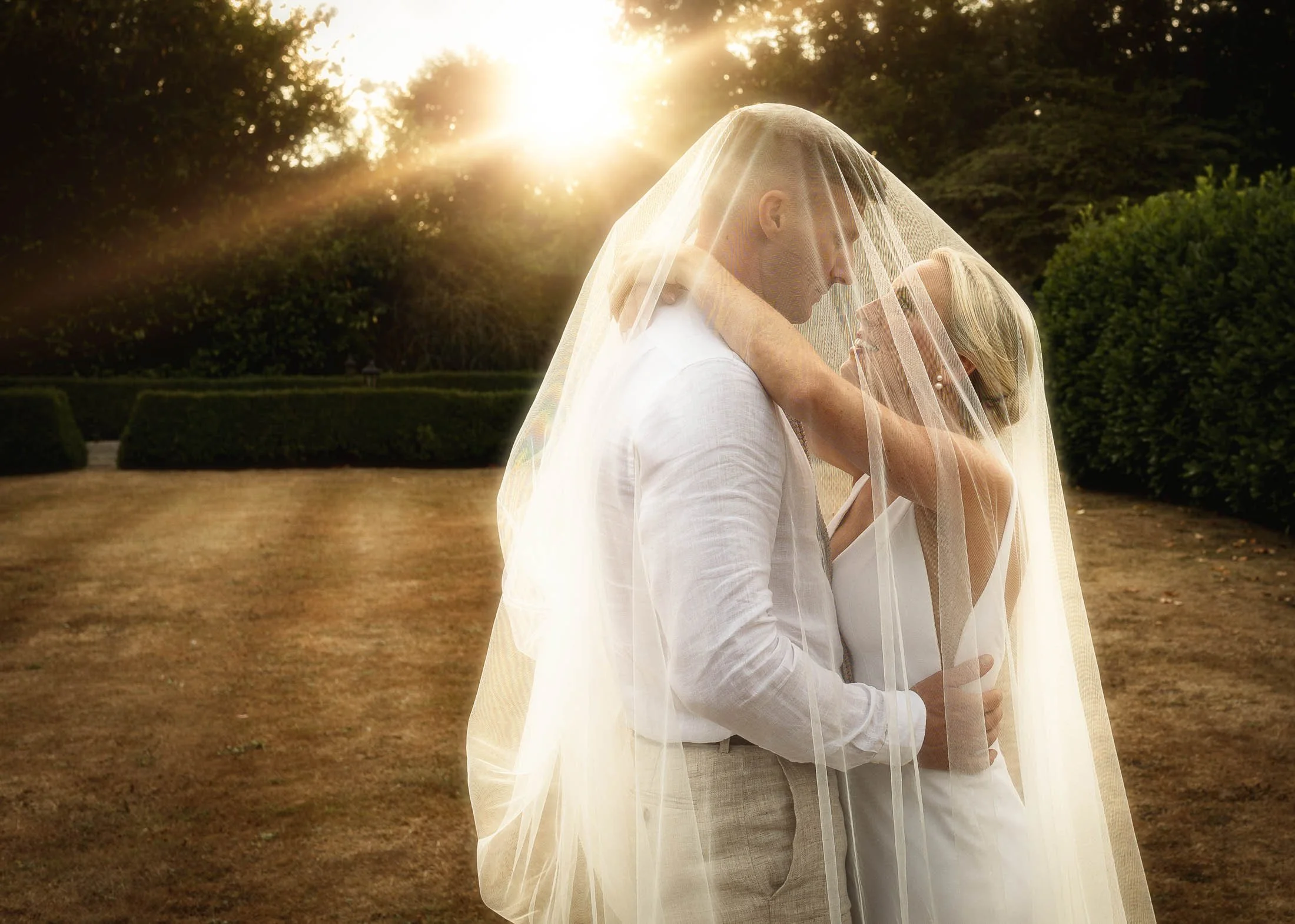 A romantic and colourful golden hour portrait of a bride and groom underneath a veil at Winters Barns, Kent.