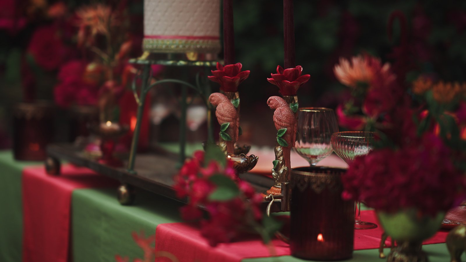 Styling detail shot showing intricate wedding decor with pink and red florals and elegant textures