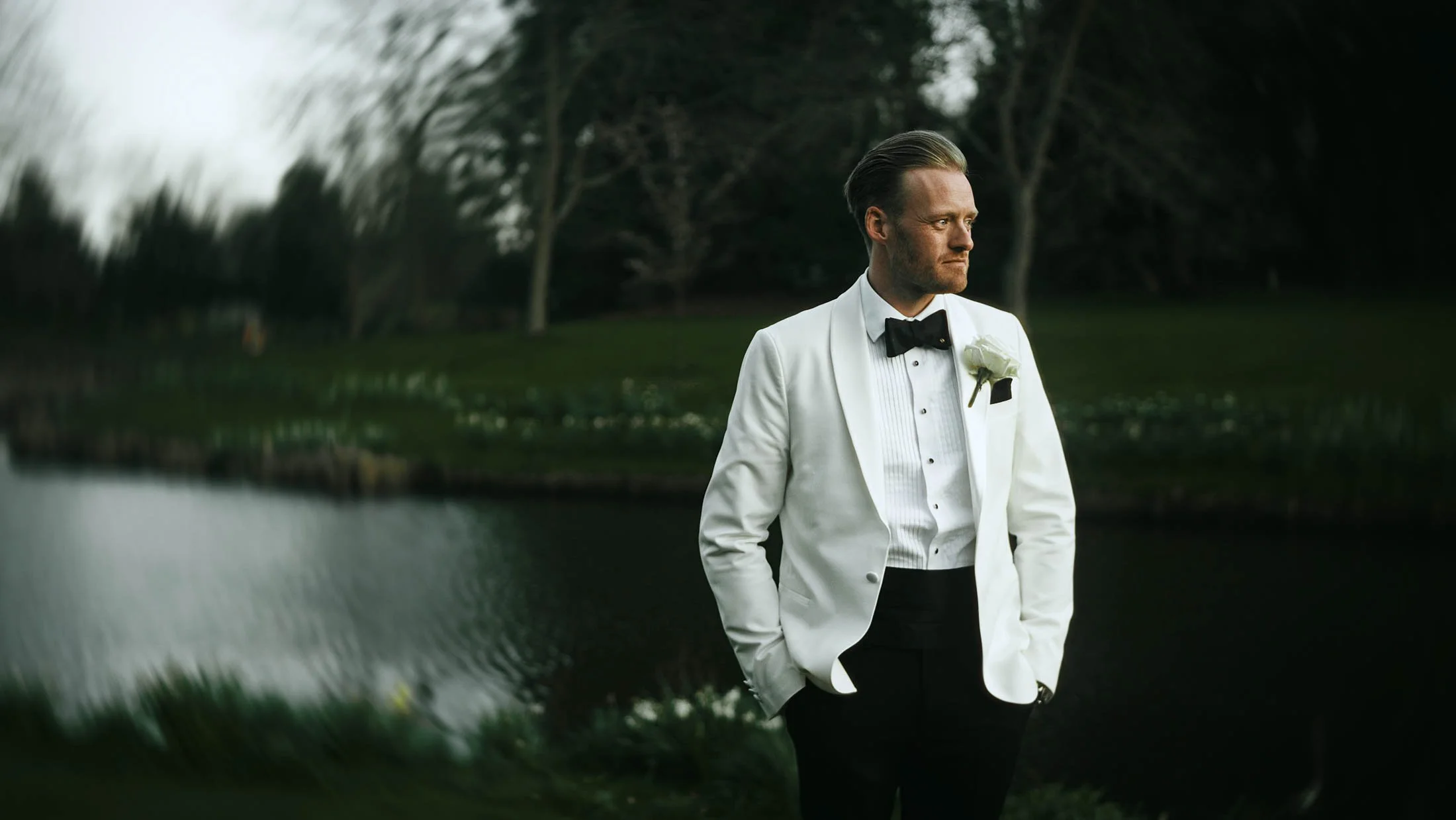 A golden hour portrait of a groom wearing black-tie with a white tuxedo at The Orangery, Maidstone, as part of his storytelling wedding film.