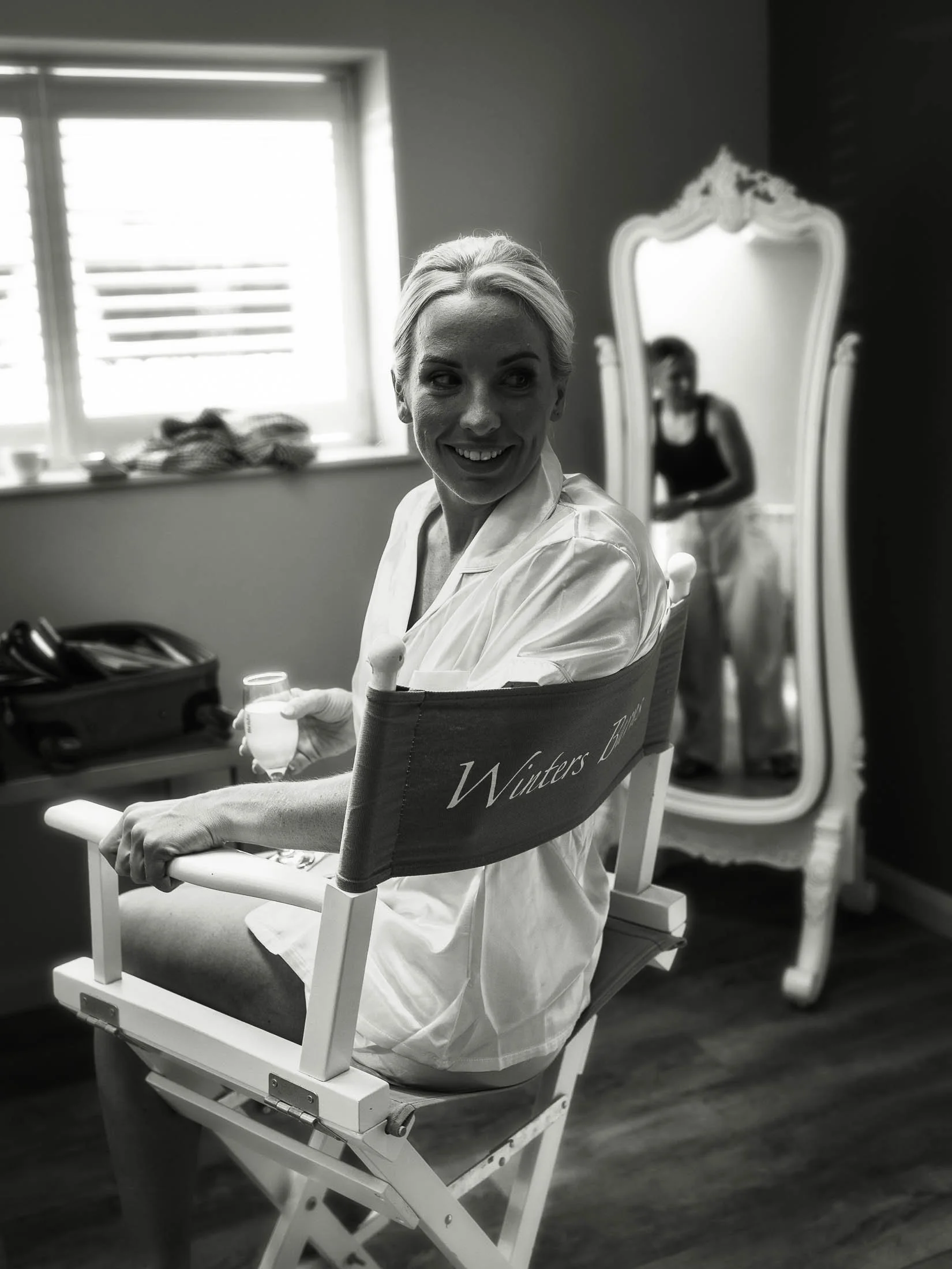 A bride laughs with her bridesmaids as she has her hair and make up applied at Winters Barns.