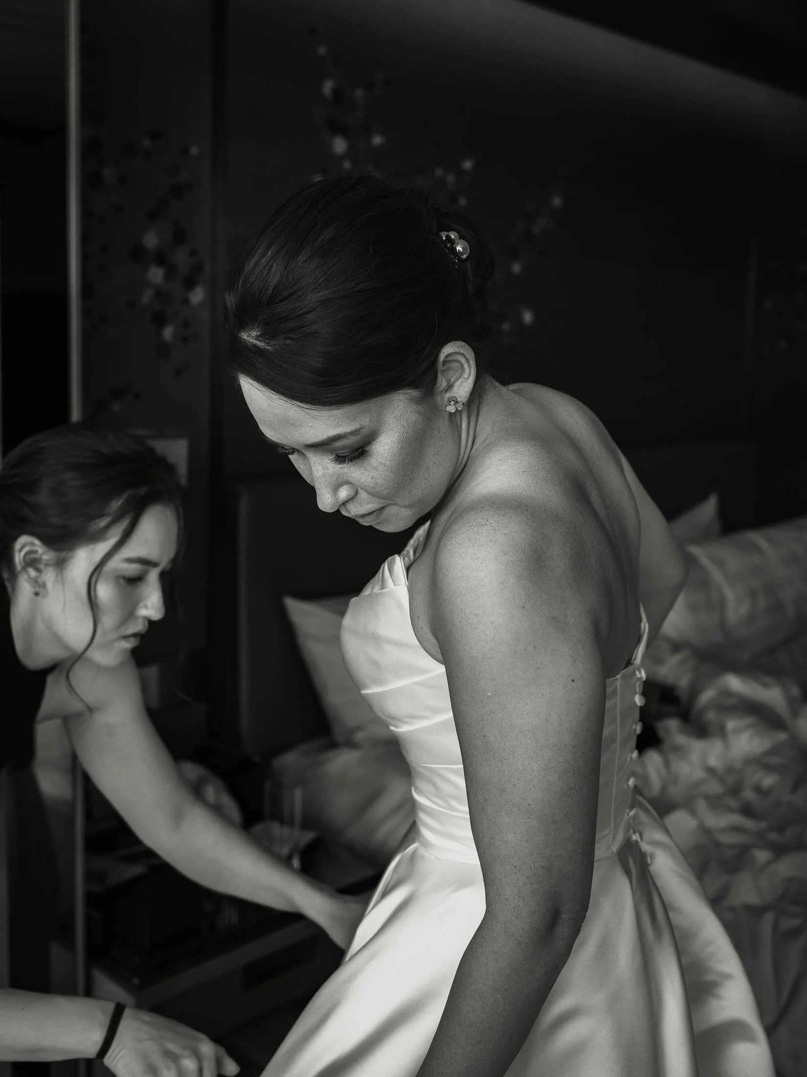 A timeless bridal portrait as the bride glances down at her wedding dress during morning preparations.