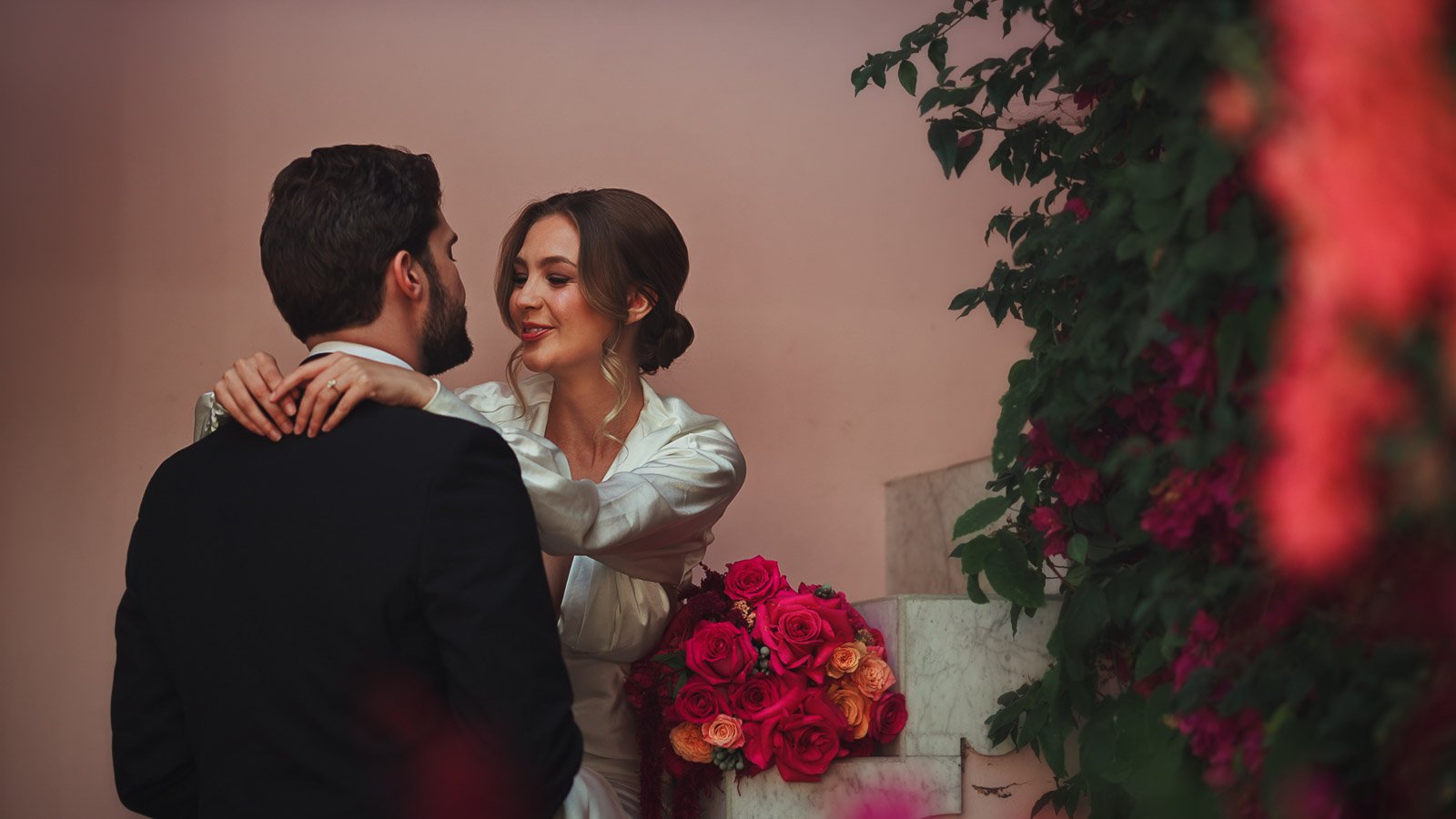 Bride and groom pose with modern black tie styling and strong palette in a courtyard setting
