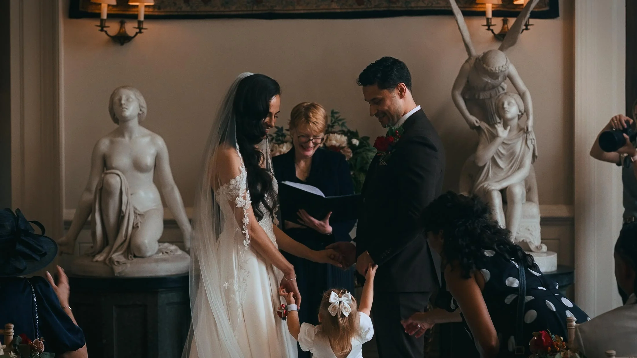 An emotional wedding ceremony moment at Elmore Court, where a young daughter holds the hands of the bride and groom.