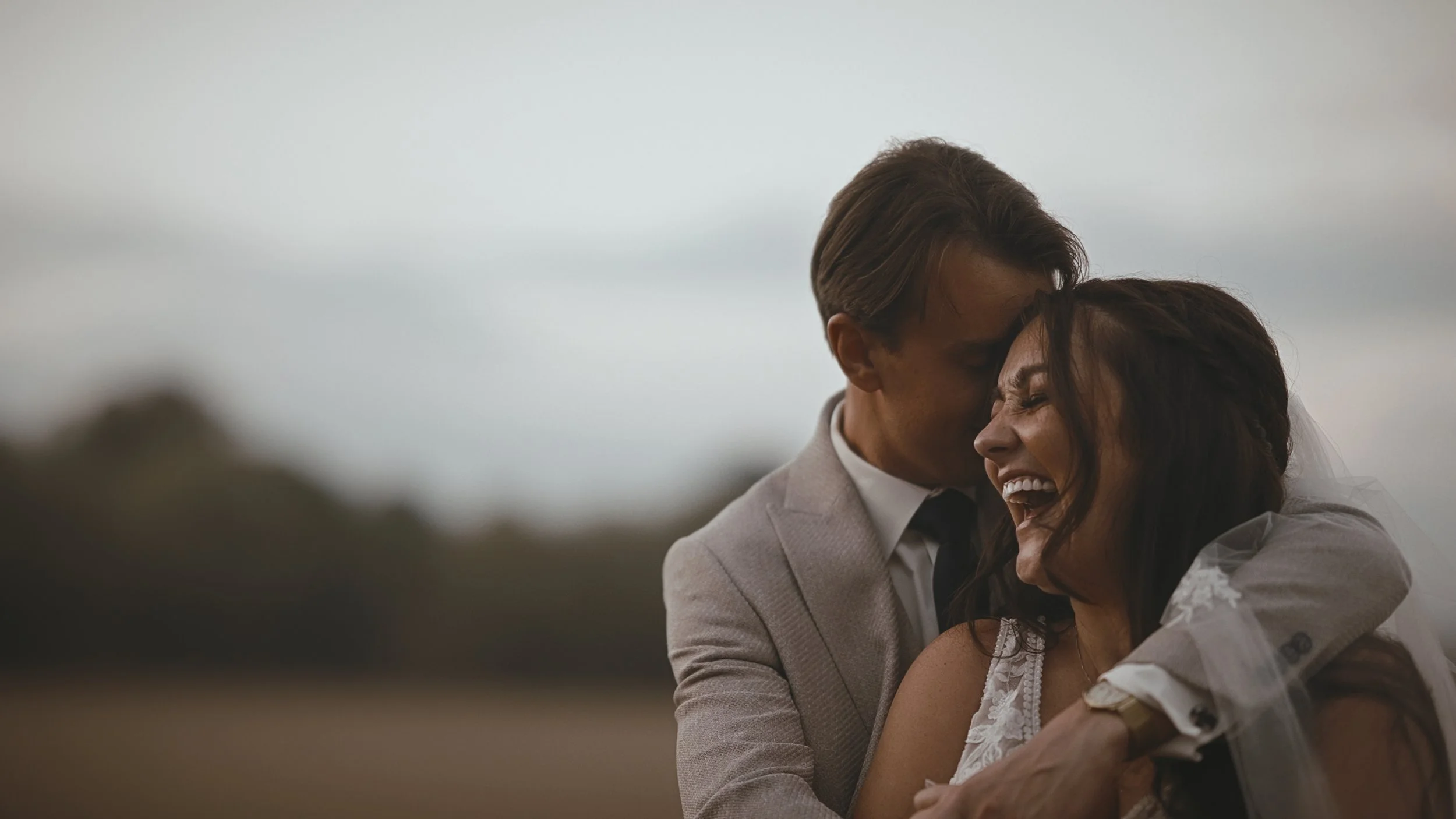 A candid golden hour moment as the bride and groom laugh together, framed editorially for a wedding video.
