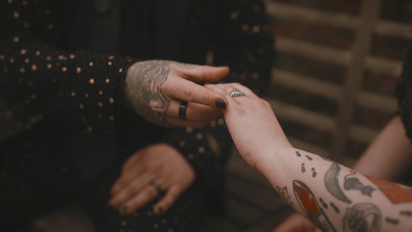 Close-up of tattooed hands during an alternative gothic-inspired wedding at Winters Barns, Kent.