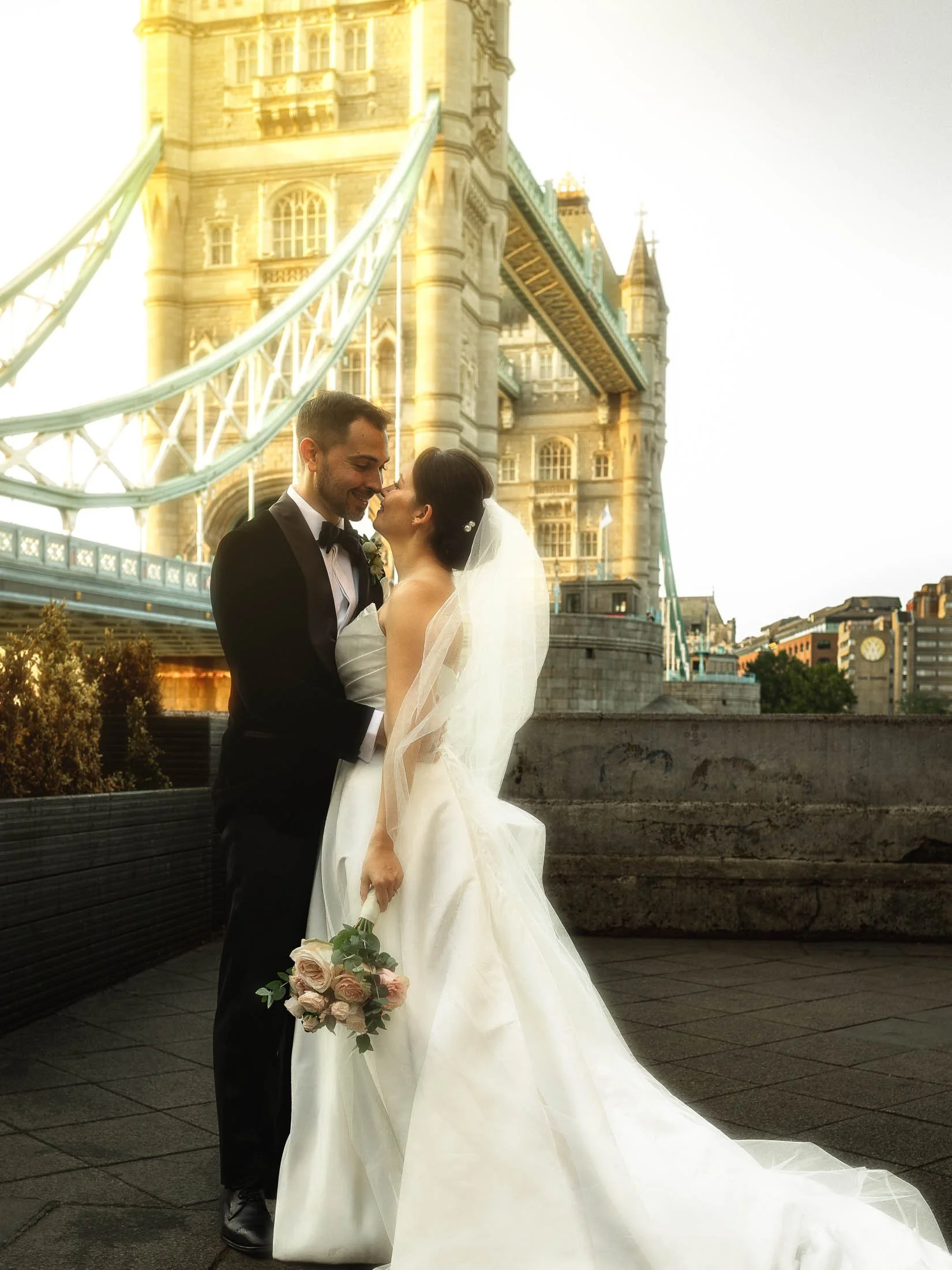 Timeless London wedding photograph showing a couple in black tie with Tower Bridge in the background, captured by a cohesive wedding photography and videography team for a Shangri-La The Shard wedding day.