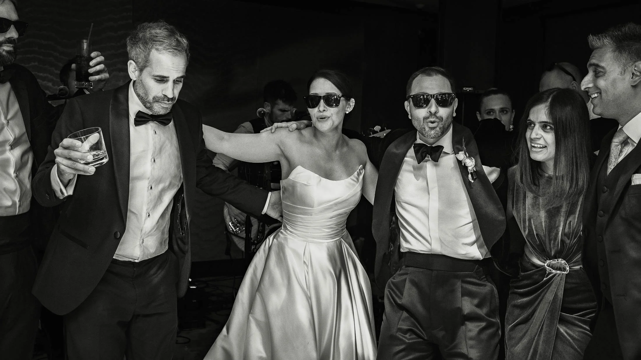 Editorial wedding after party moments as a bride and groom wear sunglasses and dance with their guests.
