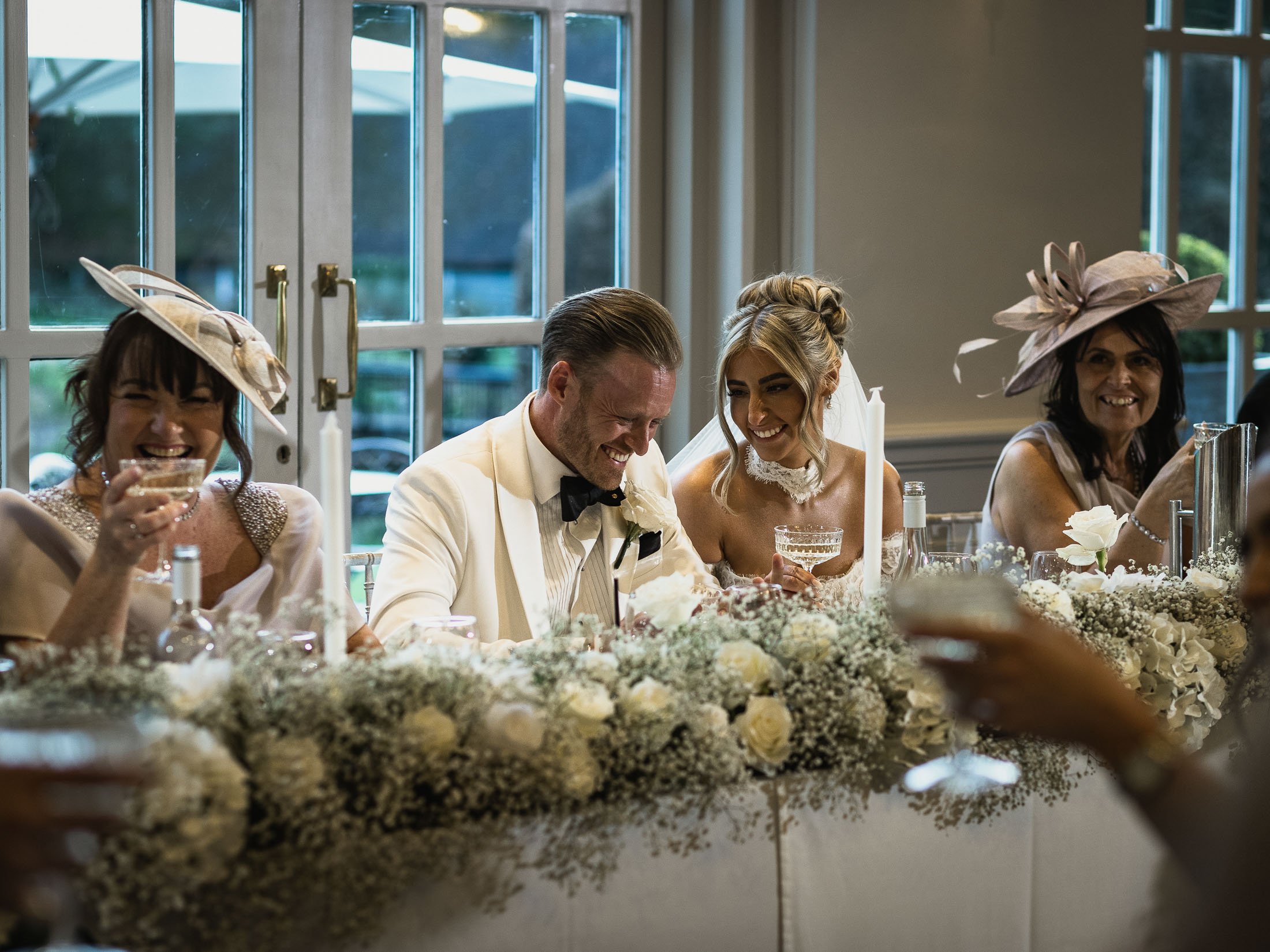 A bride and groom laughing together at the top table during speeches at The Orangery Maidstone.