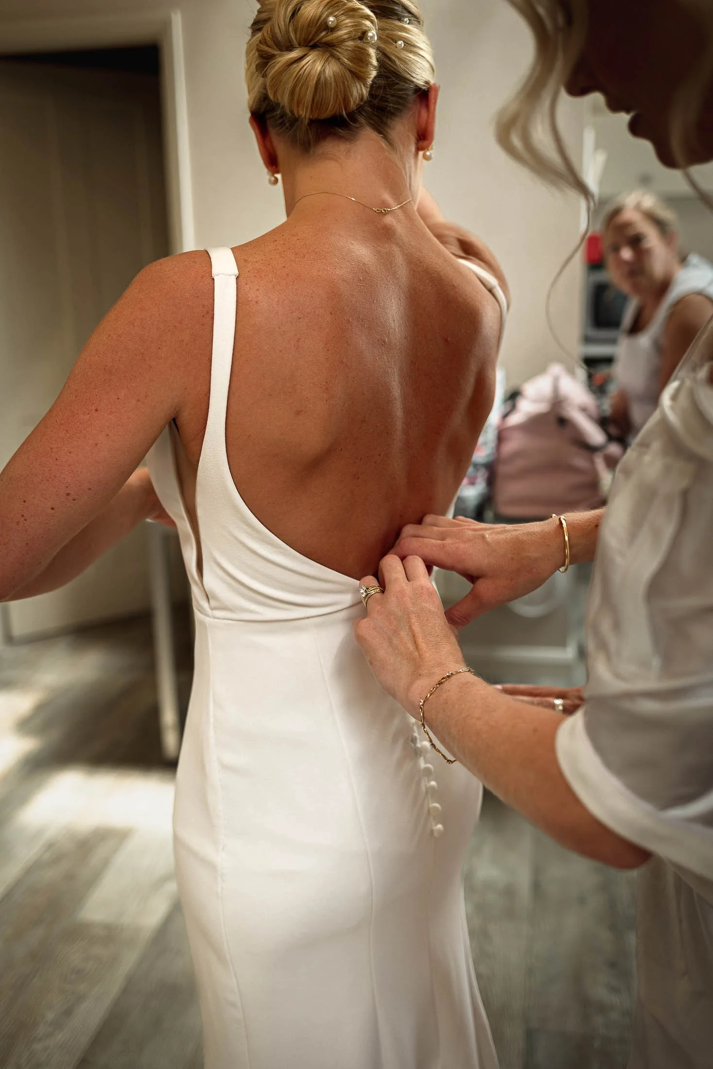 The Mother of the Bride fastens the back of the Brides dress during morning preparations at Winters Barns in Kent.