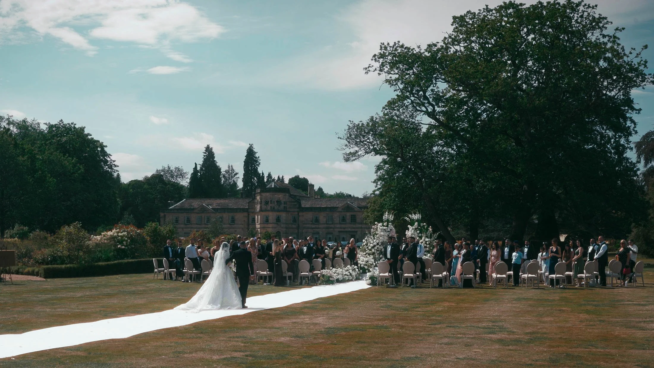 An outdoor summer wedding ceremony on the Front Lawn of the Grantley Hall wedding venue in Yorkshire.