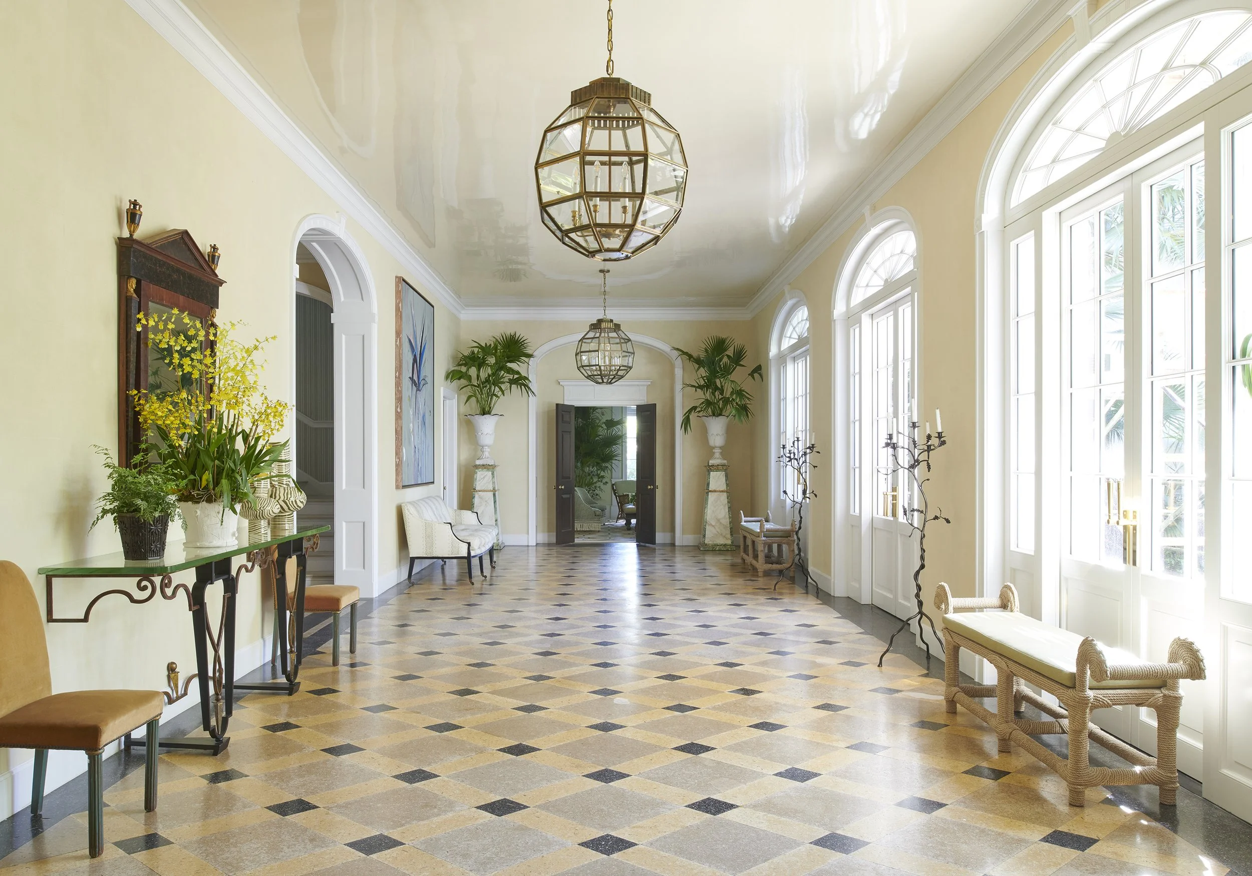 Bright, elegant interior with large arched windows, decorative plants, and classic furnishings.