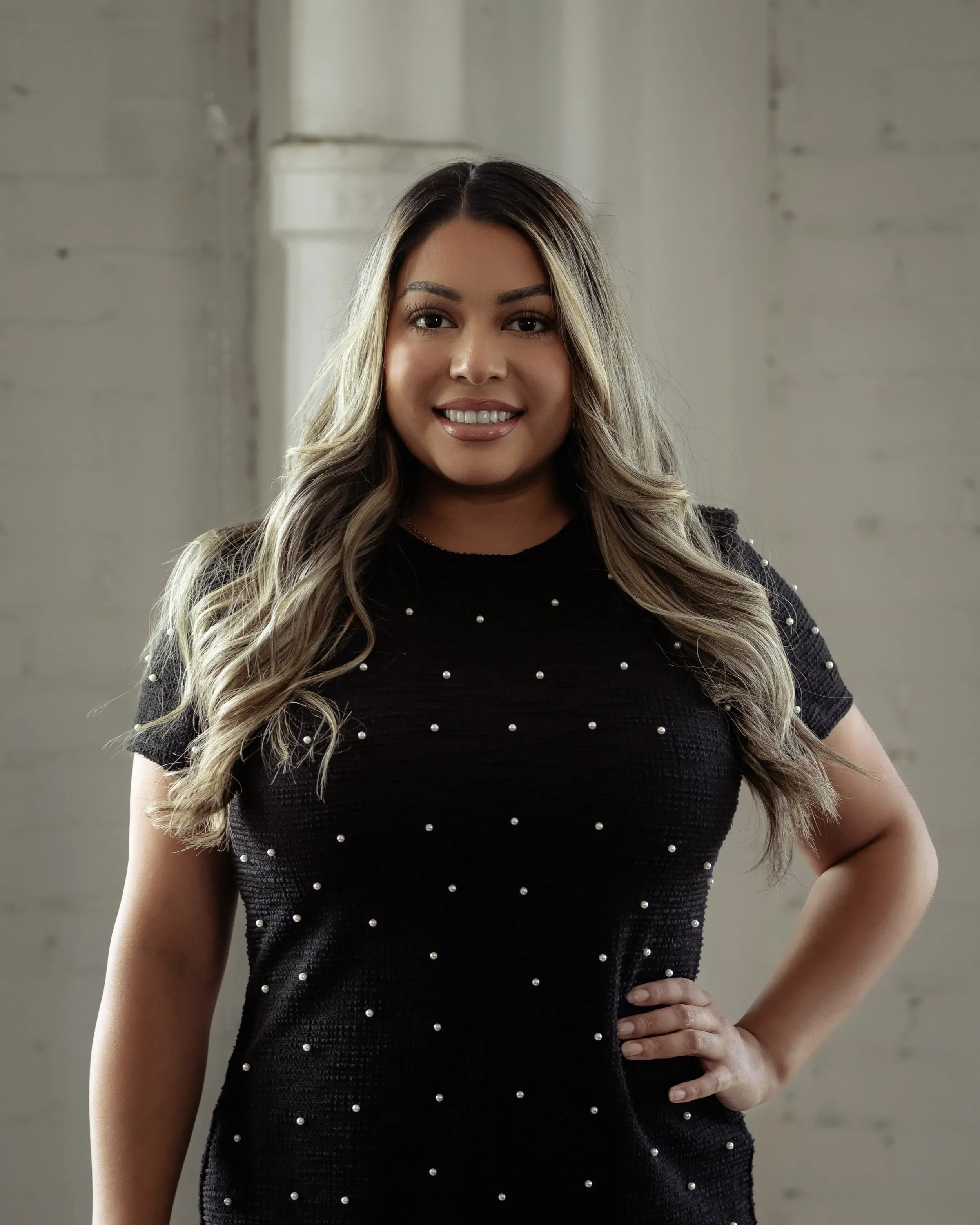 Close-up portrait of a woman with long brown hair, makeup, and a neutral expression.