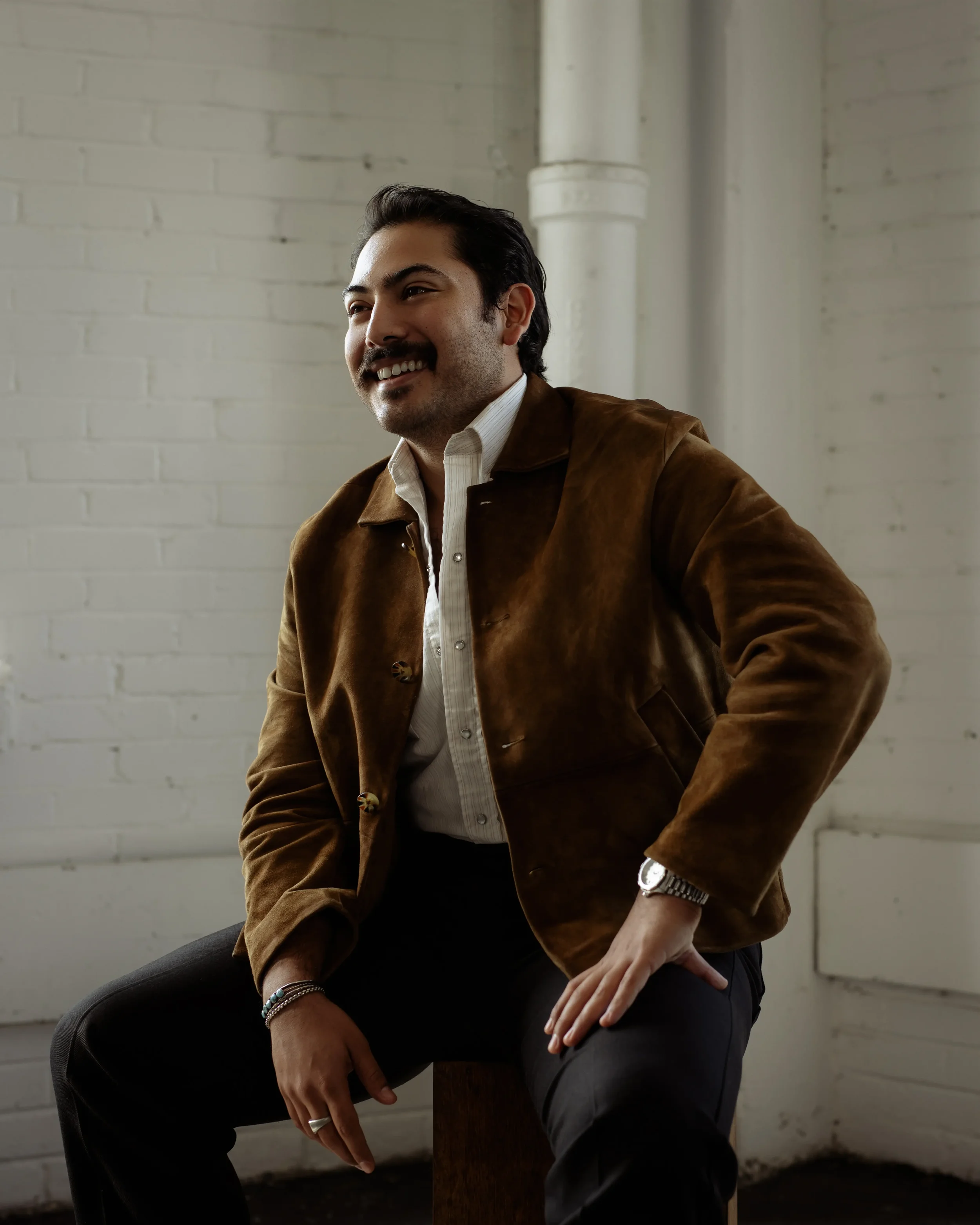 Headshot profile photo of Brandon Rodriguez posing by a stool
