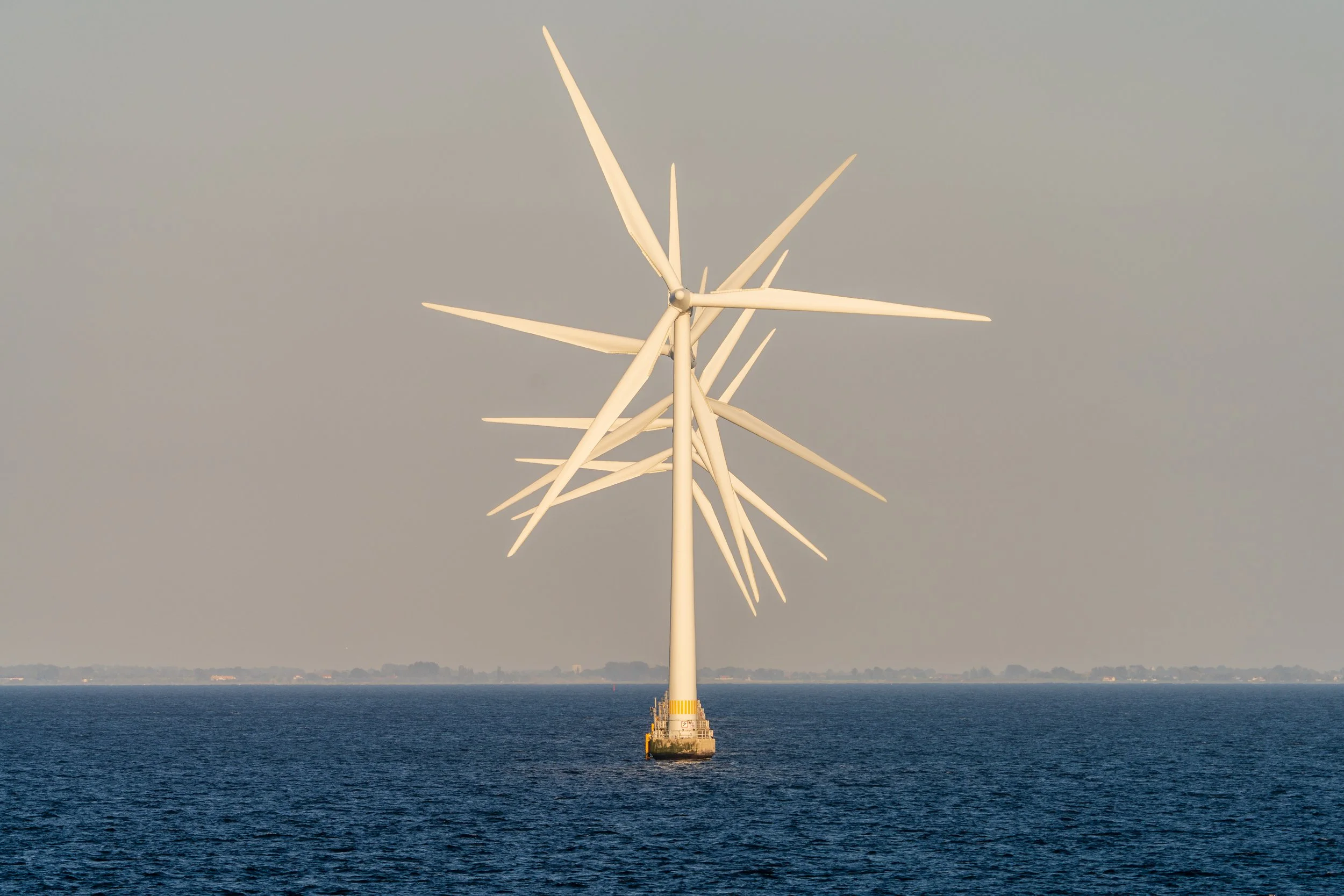 Offshore wind turbine with multiple blades in the ocean during daytime.