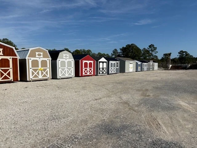 A long row of Liberty Barns and sheds with different colors at the Holly Ridge lot.