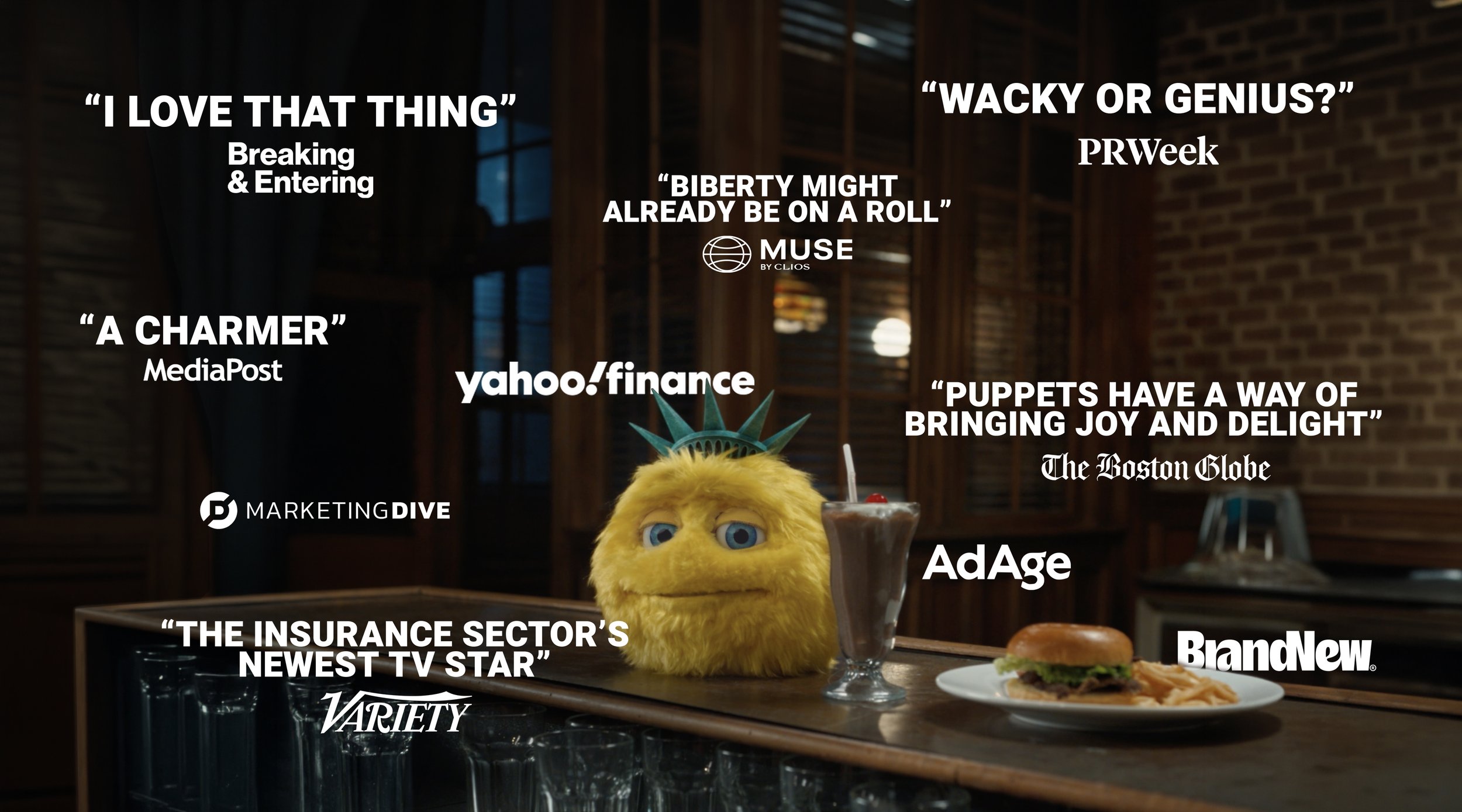 A yellow, furry puppet with blue eyes and a Statue of Liberty crown on his head, surrounded by various quotes and logos from media outlets and companies praising the new ad campaign.