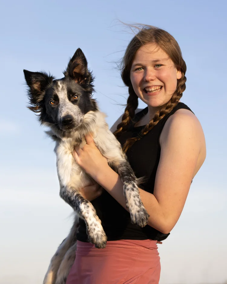 A young woman holding her Border Collie outdoors