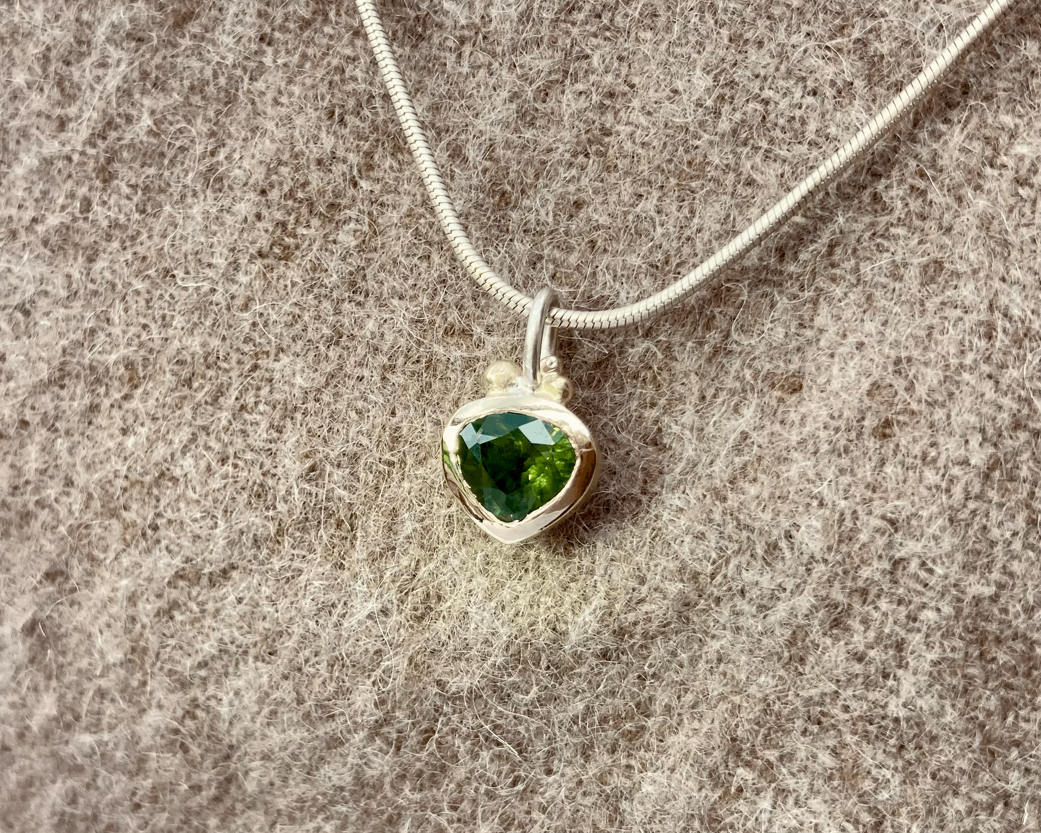 Anhänger in Silber mit Gold und einem fast herzförmigen, grünen Saphir