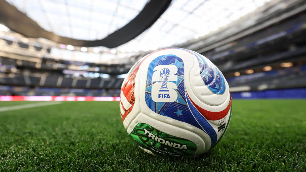 FIFA soccer ball sitting on green pitch in football stadium