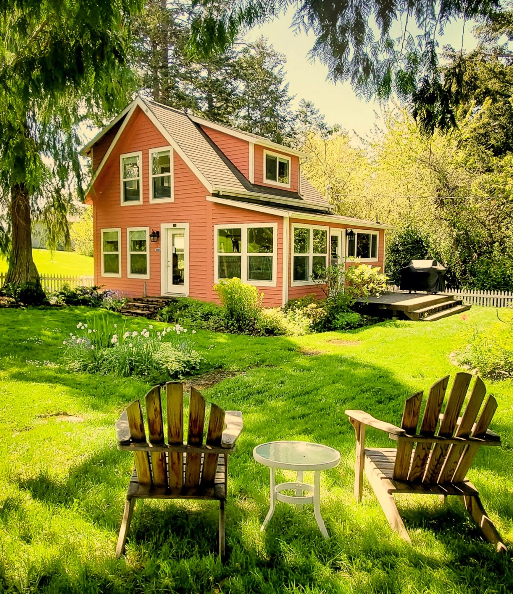 Pink two-story Homestead cabin set back with large grassy areas and two adirondack chairs in foreground. Click for More Information about the Cabins.
