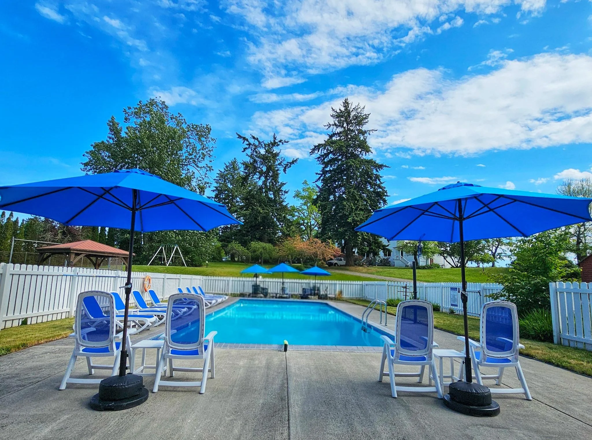 View of Chevy Chase Beach Cabins Heated Pool with Blue Lounge Chairs and Blue Umbrellas Open