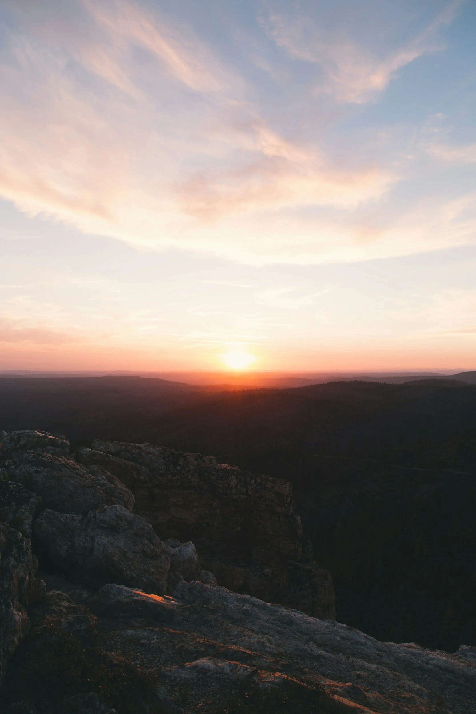 Scenic sunset over a rocky mountain landscape with a colorful sky and clouds.