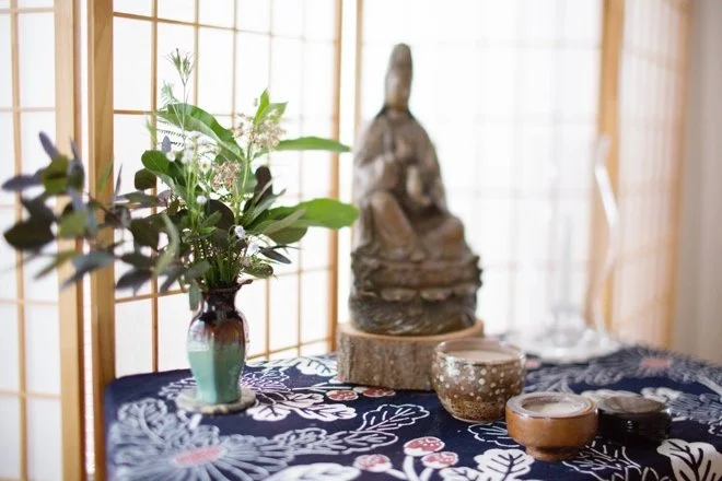 Buddhist statue next to a vase with flowers