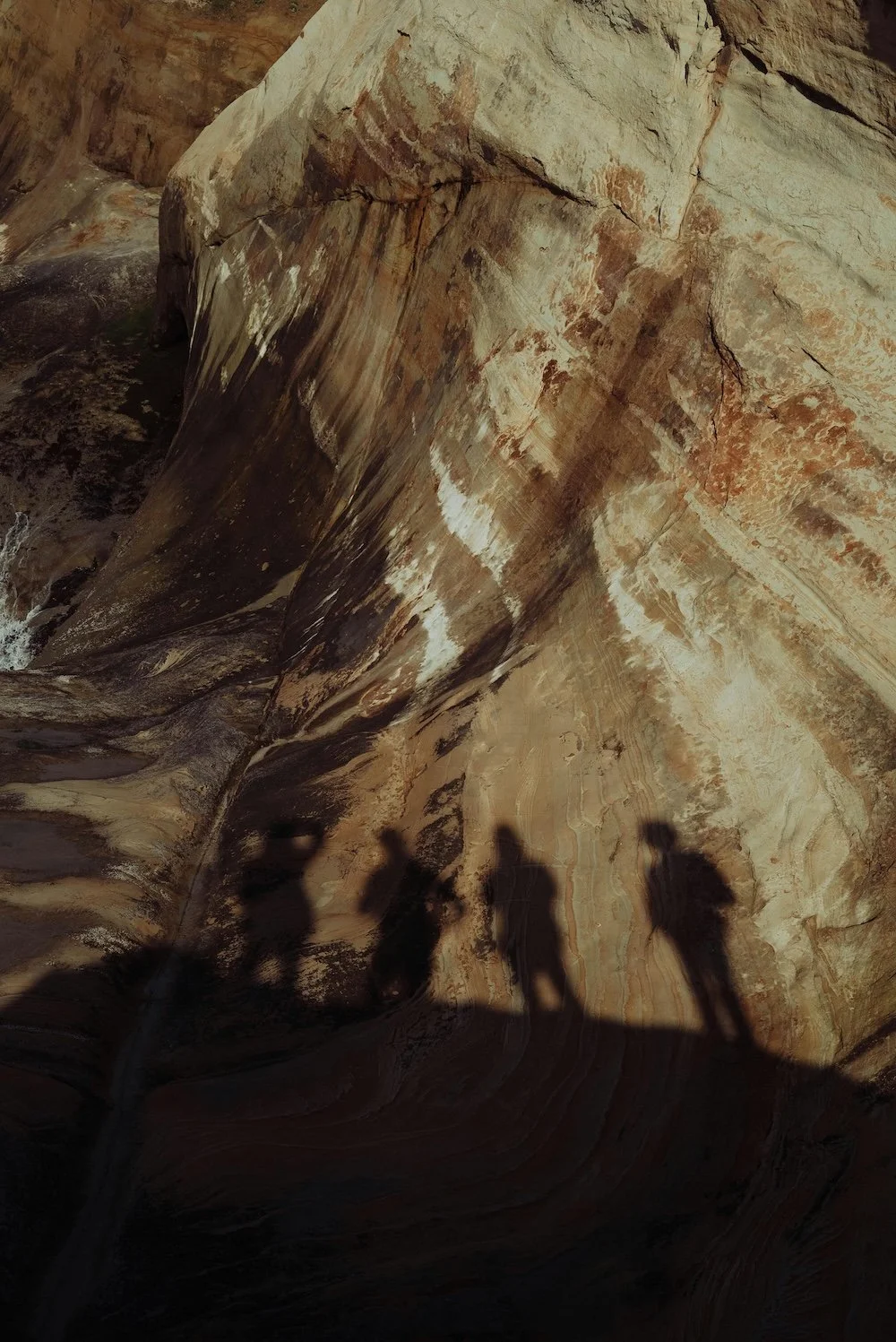 A rock wall with shadows of a group of people