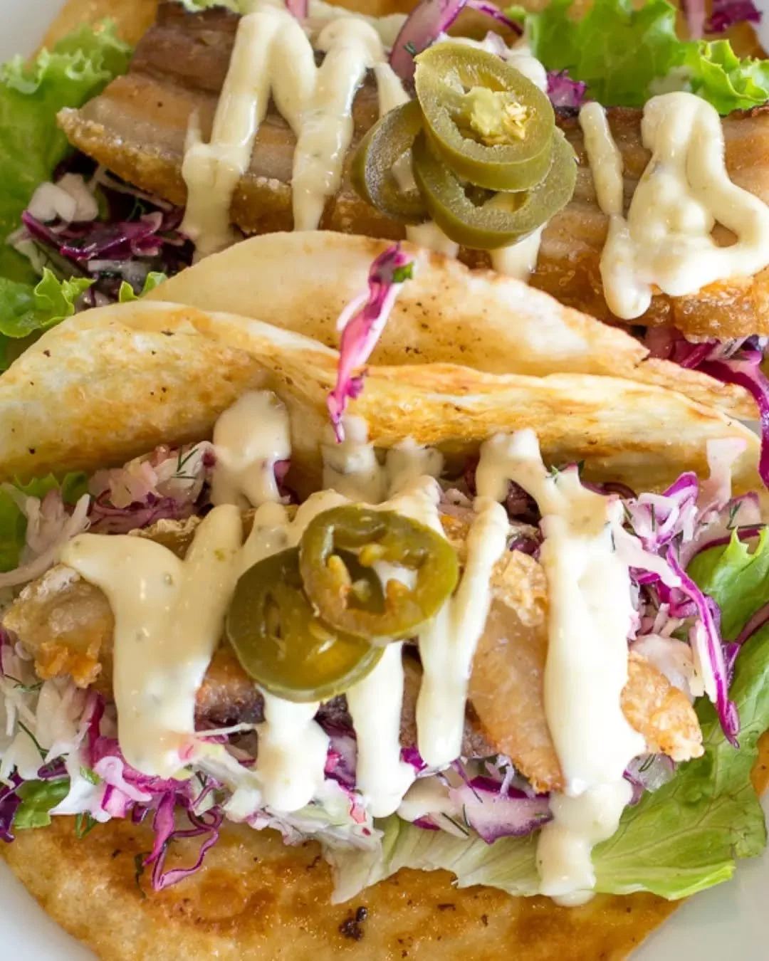 Simple, crunchy, coastal perfection. Our fish tacos are all about golden barra, zesty curtido, and a little kick of sriracha mayo.