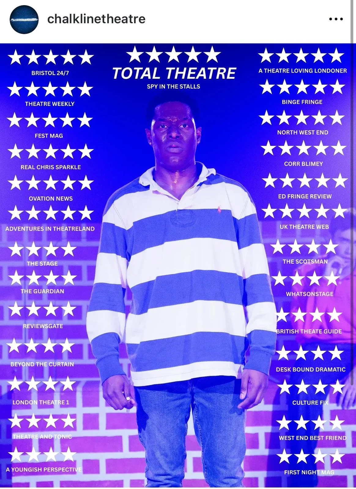 A man standing in front of a promotional poster for Total Theatre with a purple and blue background and multiple white stars, listing various theatre reviews and shows.