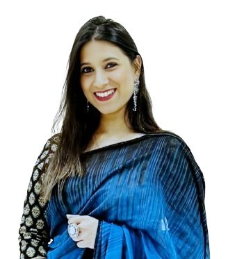 A smiling woman in a blue and black traditional Indian saree, wearing earrings and a watch, posing against a white background.