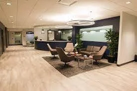 Modern hotel lobby with seating area, sofas, armchairs, coffee table, and large wall art with trees