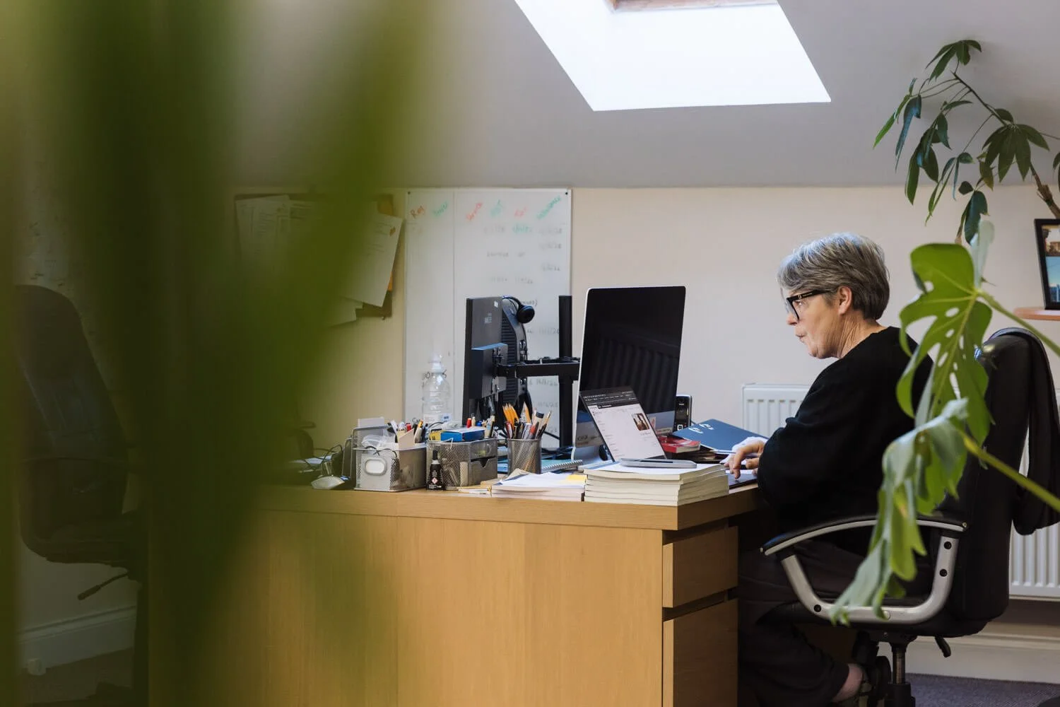 director Angela working in the BBS office green plants in the foreground