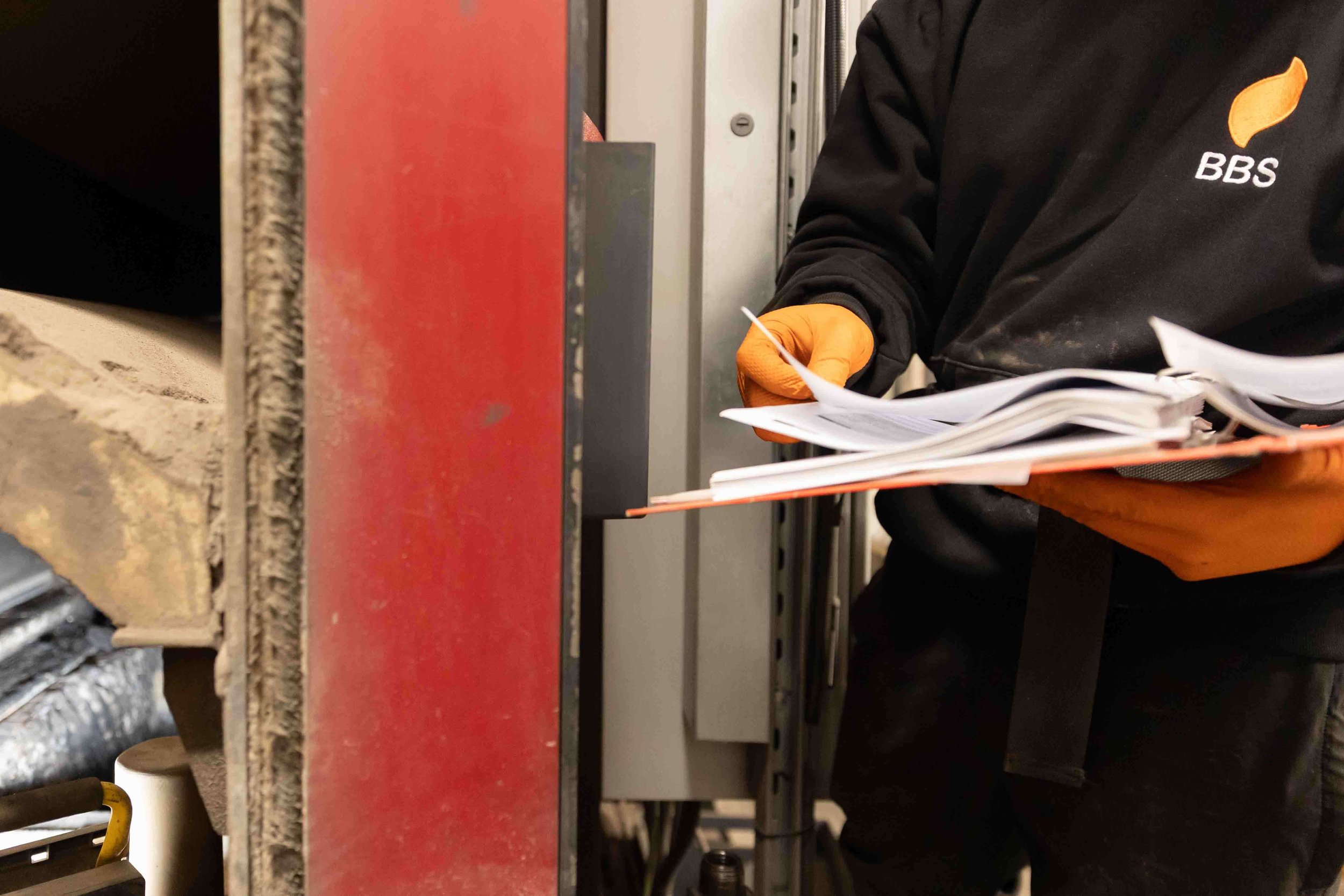 engineer checking service records in industrial boiler setting hospital plant room