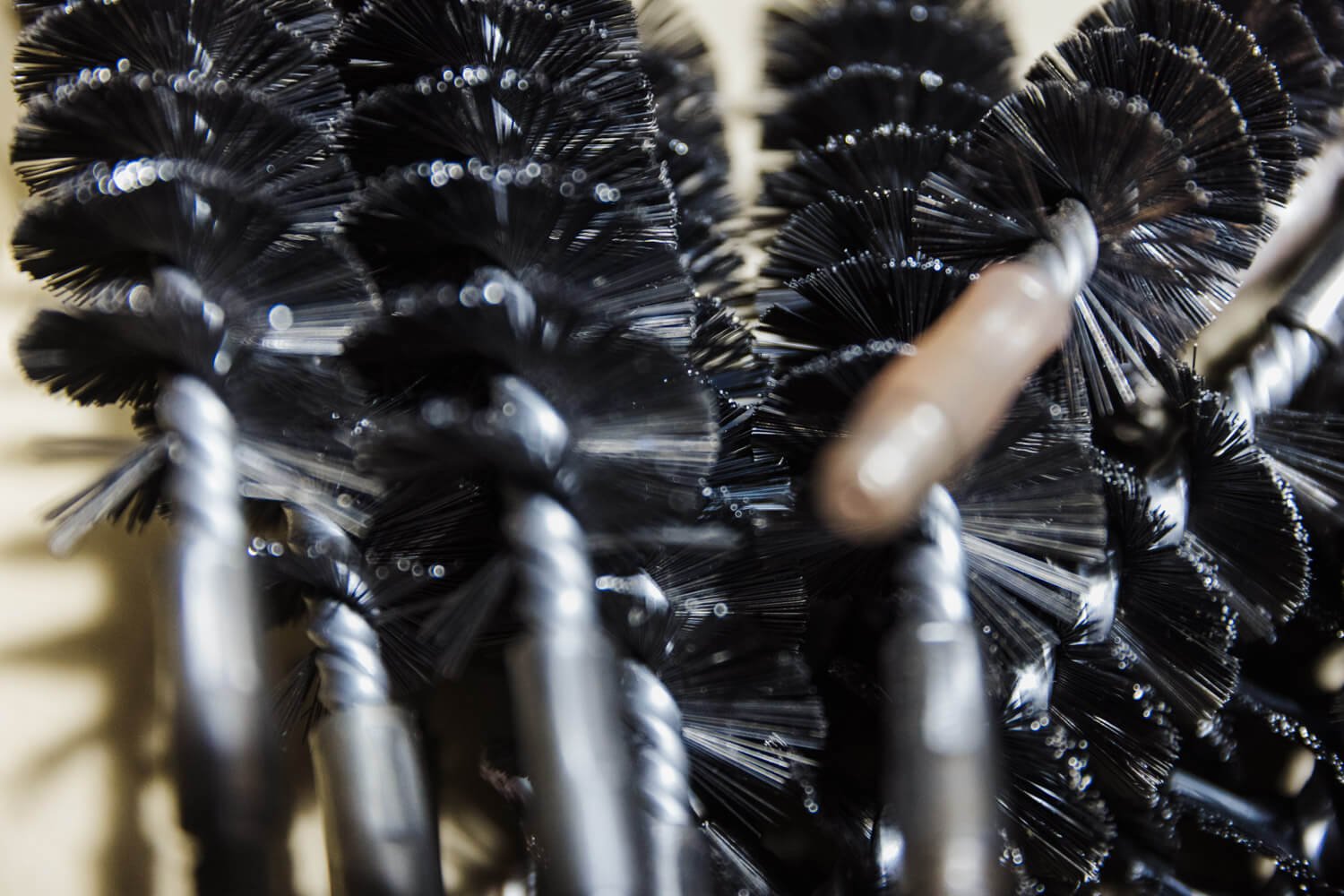 Close-up of black boiler brushes with bristles, often used by biomass boiler engineers UK, showing detailed twisted wire handles.