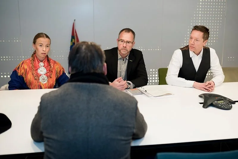 Fyra personer i ett mötesrum. En delegation pratar med en person på andra sidan skrivbordet. En samisk flagga syns i bakgrunden.
