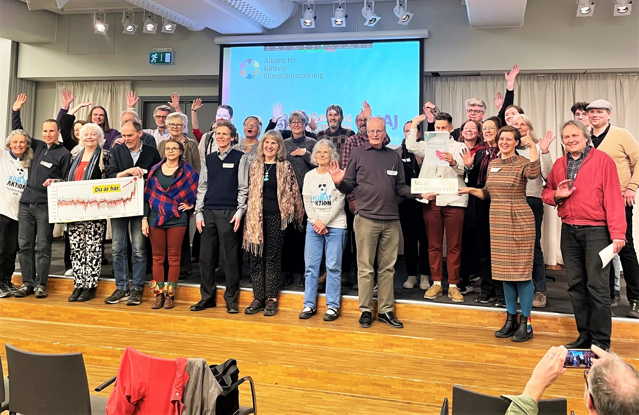 Gruppfoto av människor med händerna i luften