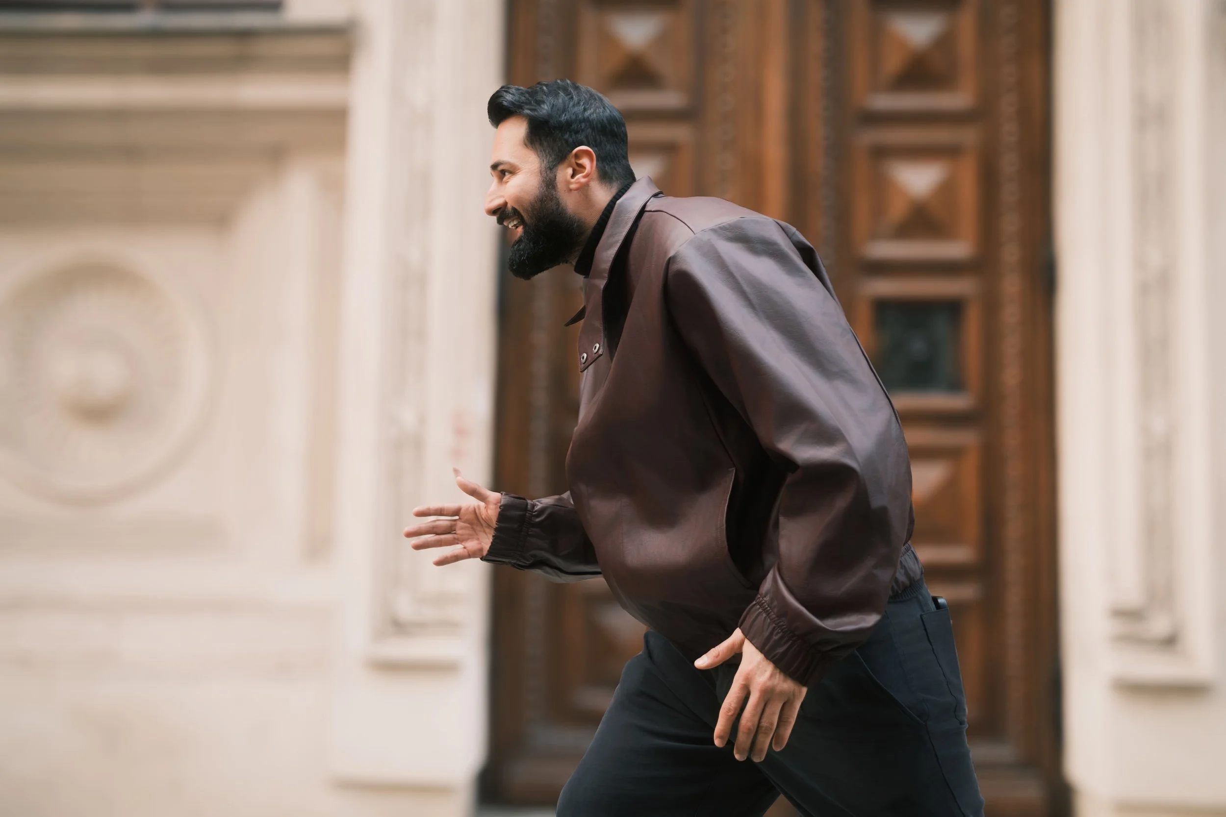Ahmed Hatem running through an interior space in front of a decorative wooden door, introducing motion against a static architectural background.